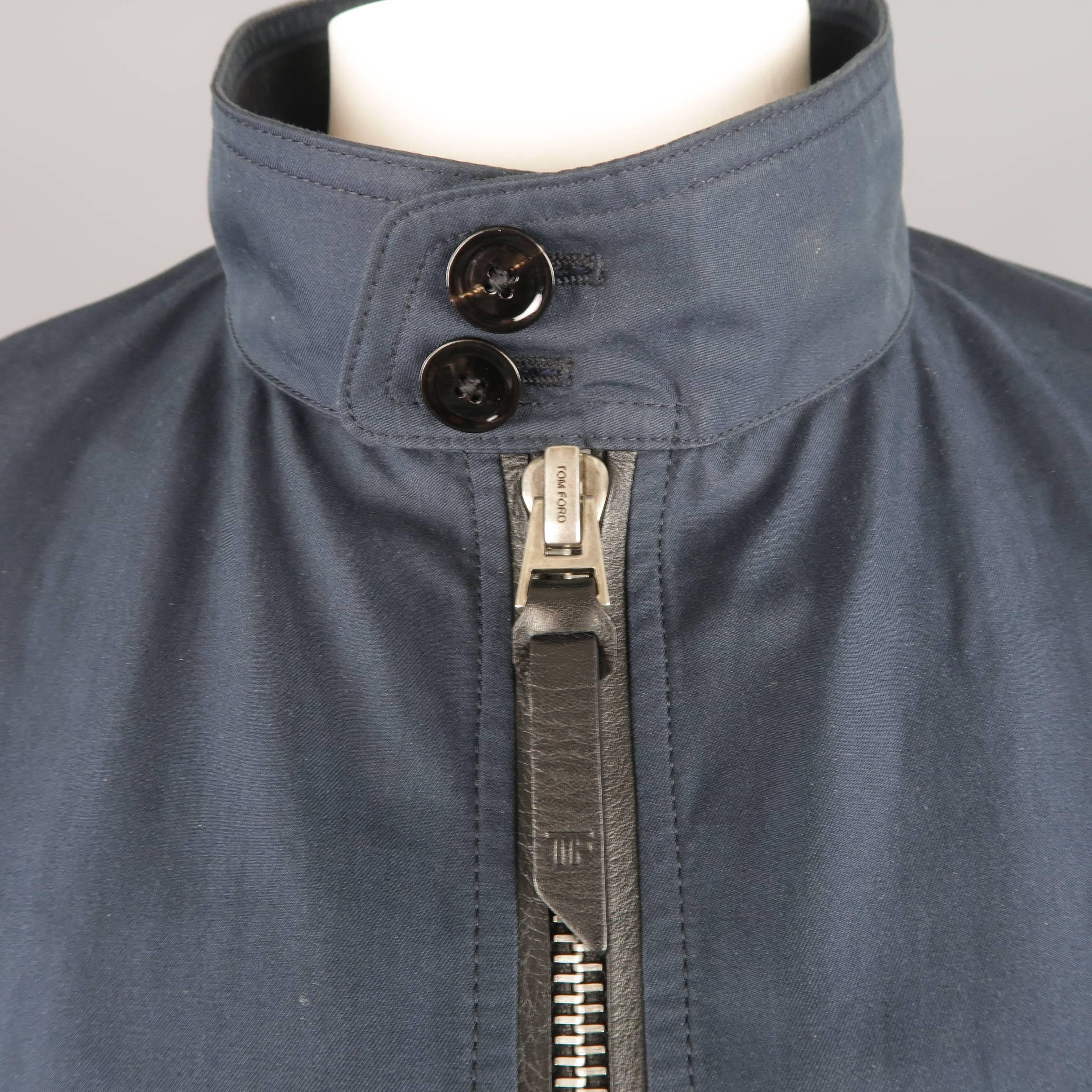 Tom Ford bomber jacket comes in muted navy blue cotton twill with a stand up button tab collar, leather trimmed silver tone double zip front with tab, slanted flap pockets, ribbed knit cuffs and hem , and plaid liner. Made in Italy.
 
Good Pre-Owned