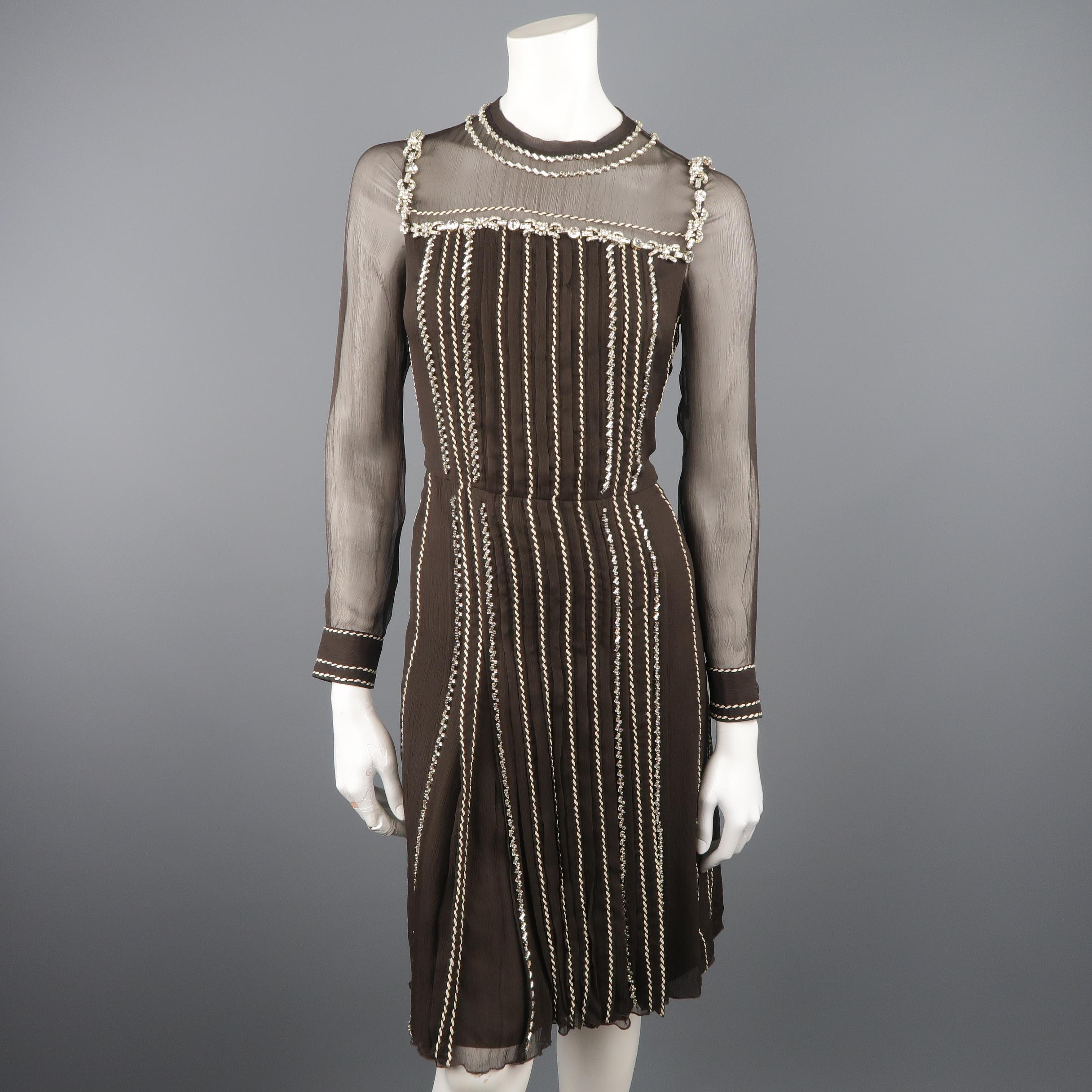 This gorgeous PRADA cocktail dress comes in a chocolate brown textured silk chiffon with a round neckline, sheer chest and long sleeves, pleated skirt, contrast whipstitch details, and crystal piping throughout. With belt. Made in Italy.
 
Excellent