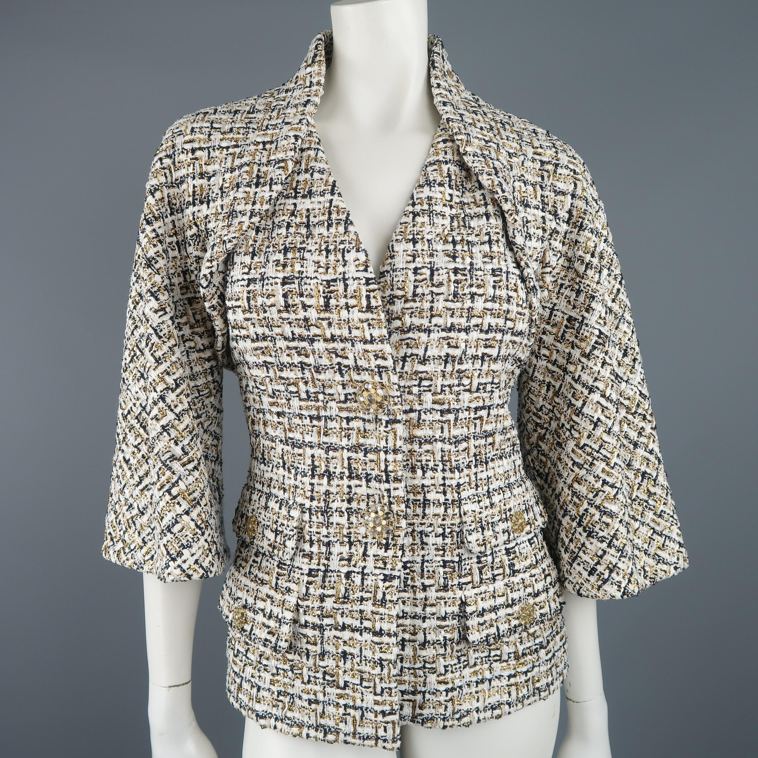 This gorgeous Chanel jacket comes in white tweed with navy blue and metallic gold weave pattern and features a v neckline,  bolero effect overlay, cropped bell sleeves, gorgeous gold tone metal flower jewelry buttons with clear gems, and four flap