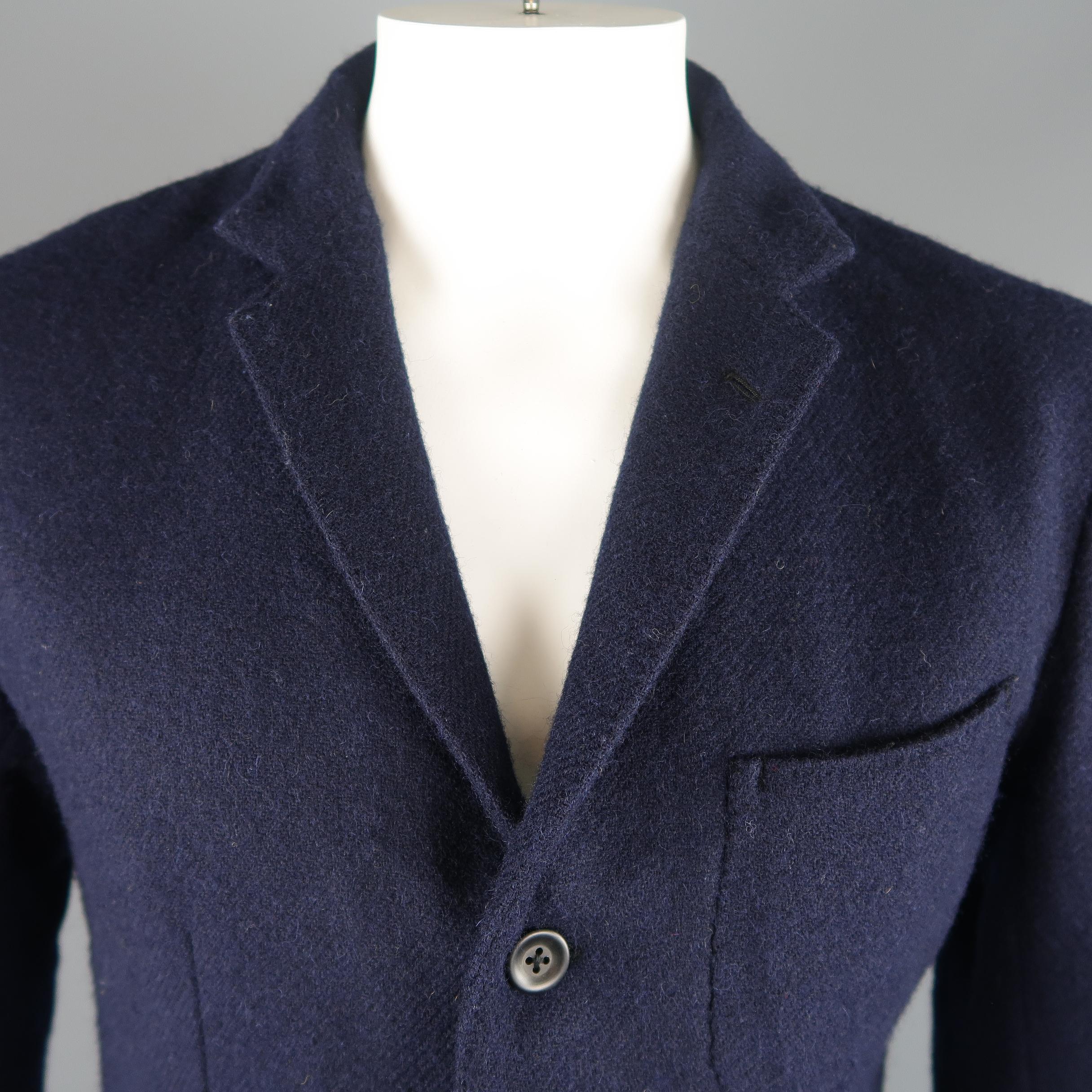 Single breasted 45RPM relaxed casual sport coat jacket comes in navy blue heavy wool twill with leather trimmed collar, notch lapel, three button front, functional button cuffs, and patch pockets. Made in Japan.
 
Excellent Pre-Owned Condition.