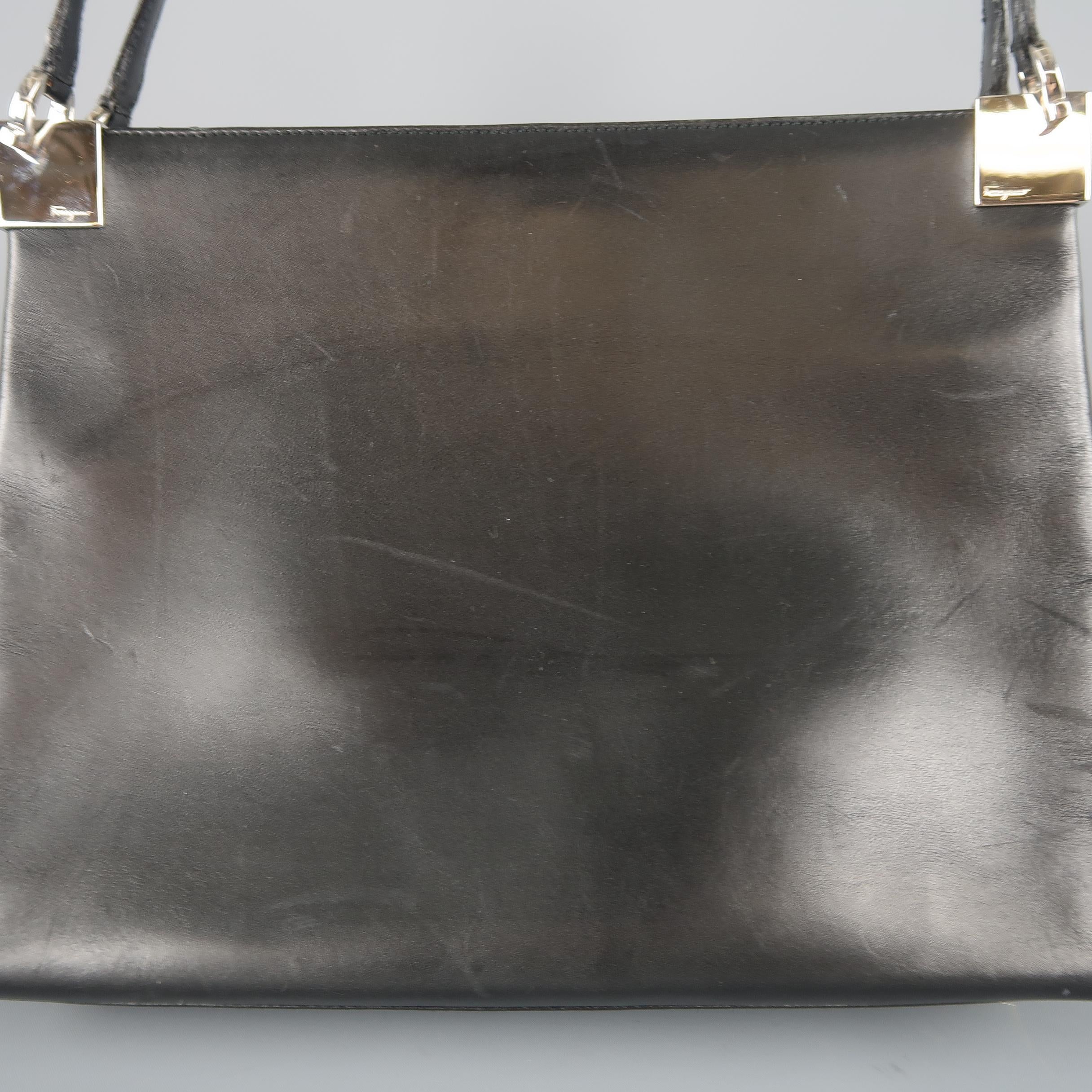 Vintage SALVATORE FERRAGAMO shoulder bag comes in smooth black leather with a double compartment interior, snap top closure, silver tone metal Gancini bit embossed hardware, and double leather shoulder straps. Wear throughout. As-is. Made in Italy.
