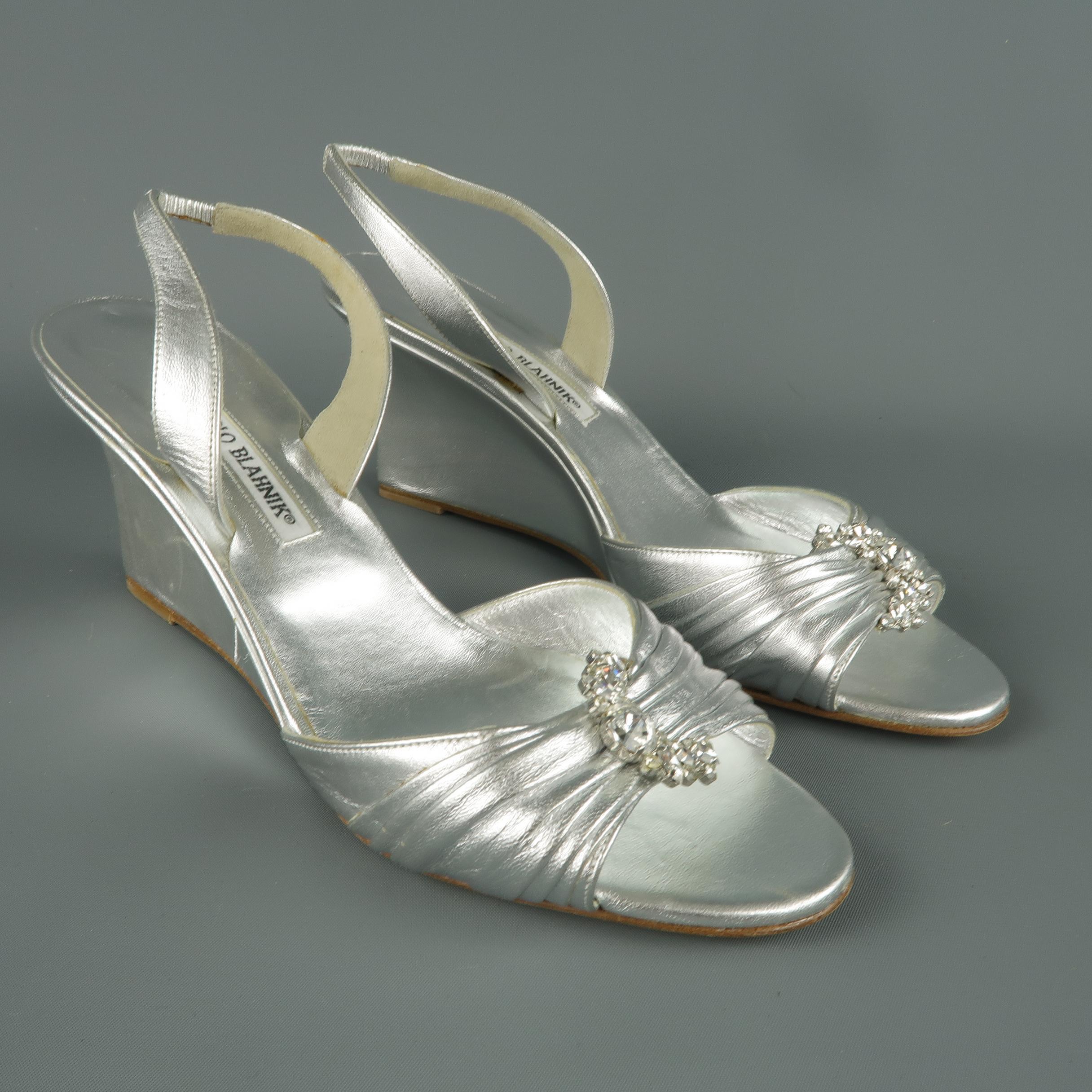 MANOLO BLAHNIK sandals come in metallic silver leather with a gathered toe strap adorned with a rhinestone brooch, slingback, and covered wedge. Handmade in Italy.
 
Good Pre-Owned Condition.
Marked: IT 40.5
 
Measurements:
 
Heel: 3 in.