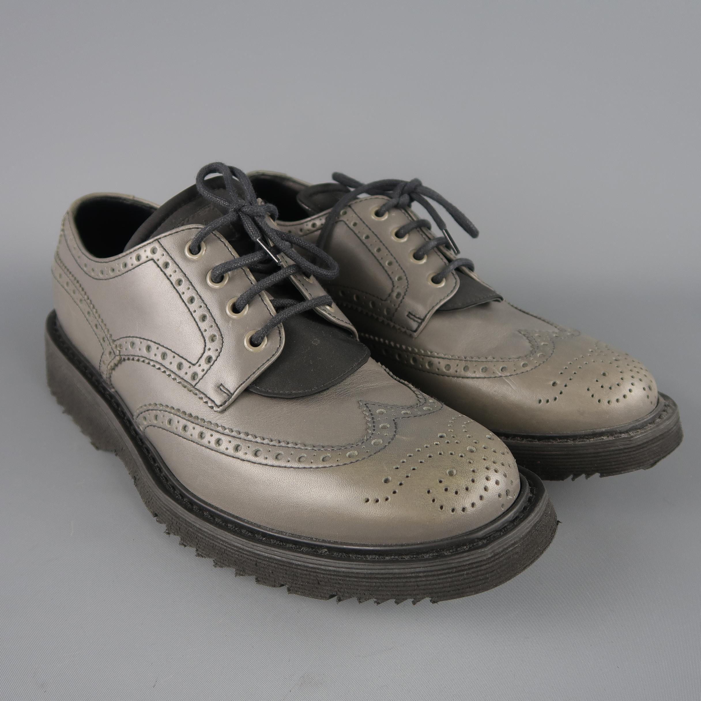 Prada shoes come in gray leather with a wingtip, perforated brogue trim, nylon padded logo tongue, and thick rubber sole. Discolorations and wear throughout. As-is. Made in Italy.
 
Fair Pre-Owned Condition.
Marked: UK 8