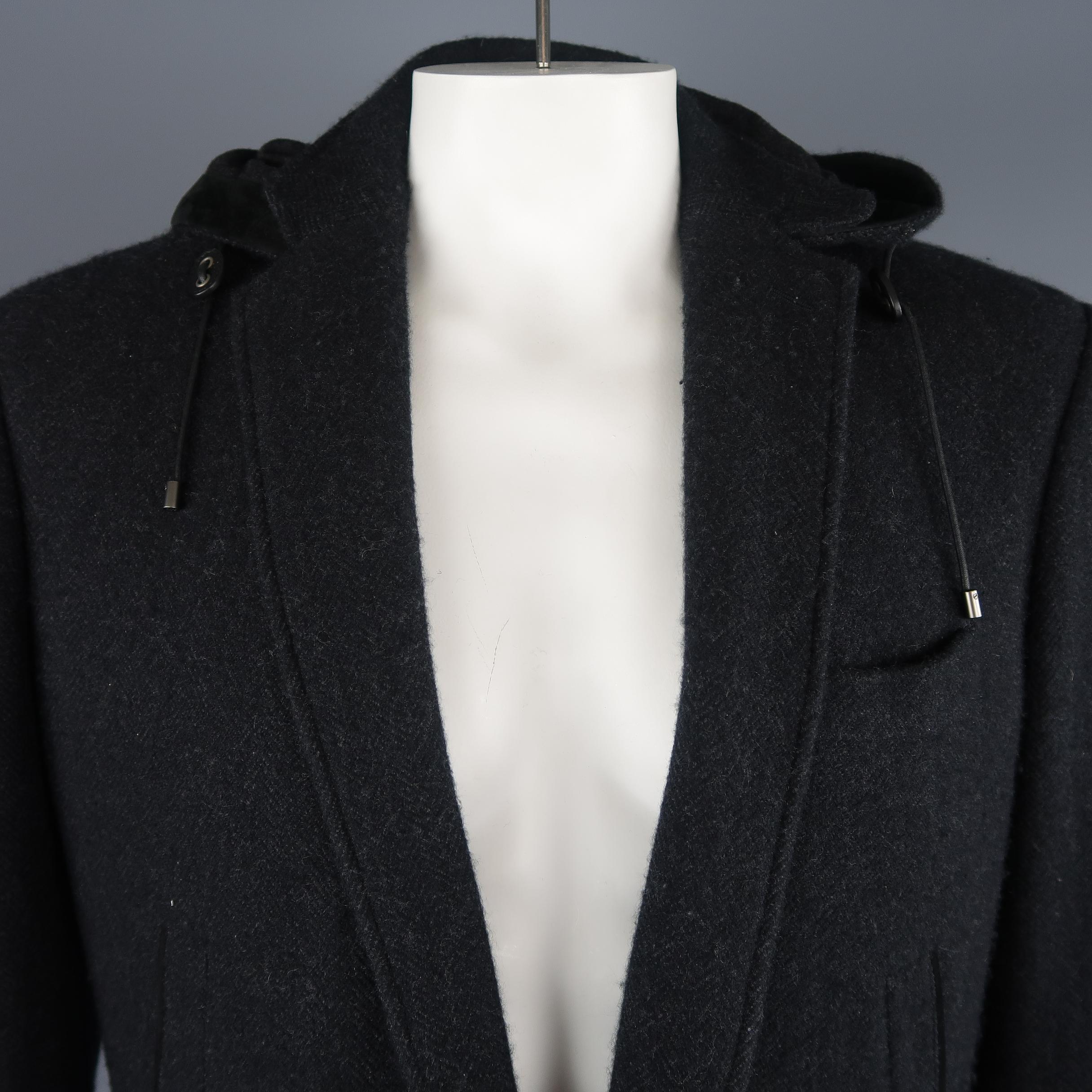 Ralph Lauren Purple Label sport jacket comes in black and charcoal cashmere herringbone with a notch lapel, two button closure, slanted pockets, patch flap military style pockets, leather piping, and a detachable hood. Minor wear. Made in Italy.
