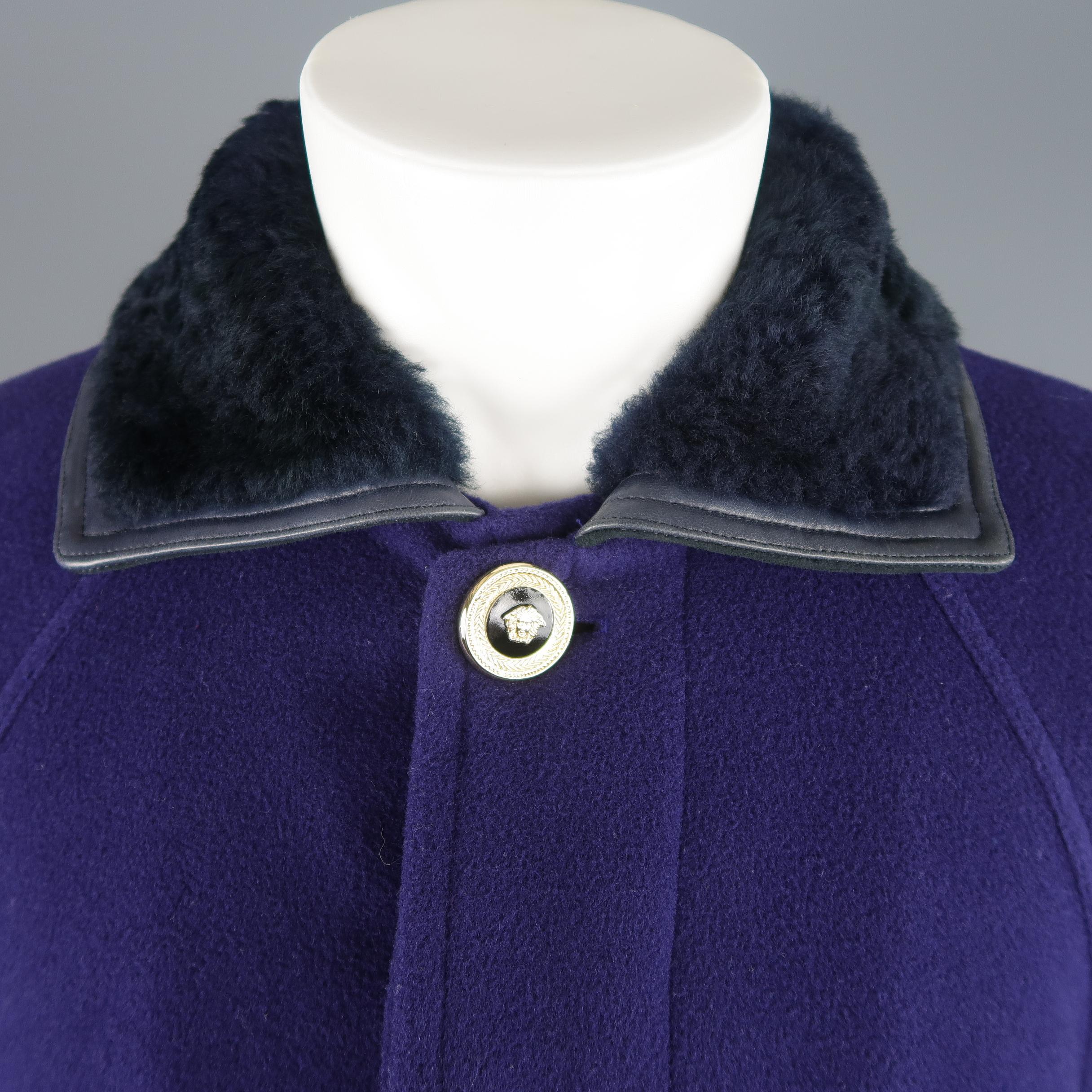 Vintage 1990's Gianni Versace coat comes in purple wool felt with a hidden placket button closure, gold tone enamel Medusa buttons, raglan sleeves, quilted back belt, and leather trimmed shearling fur collar. Made in Italy.
 
Good Pre-Owned