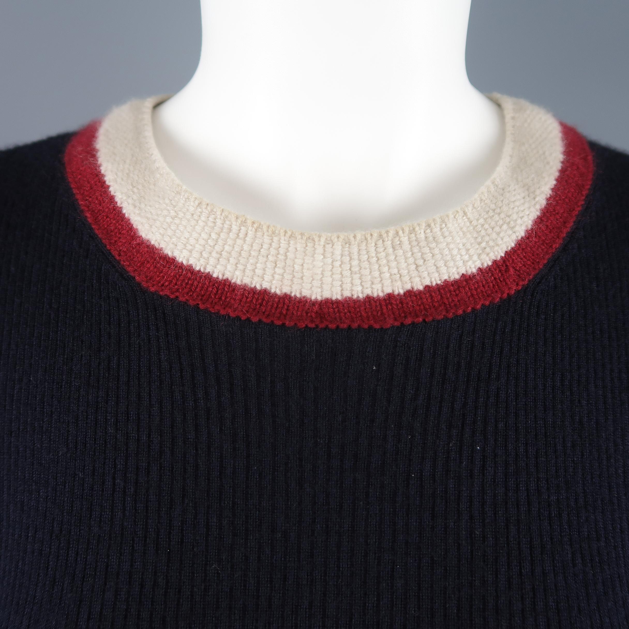Chanel pullover sweater comes in navy blue ribbed knit with a round neckline, black enamel logo plaque, and khaki and burgundy striped trim. Made in Italy.
 
Excellent Pre-Owned Condition.
Marked: FR 40
 
Measurements:
 
Shoulder: 14 in.
Bust: 30