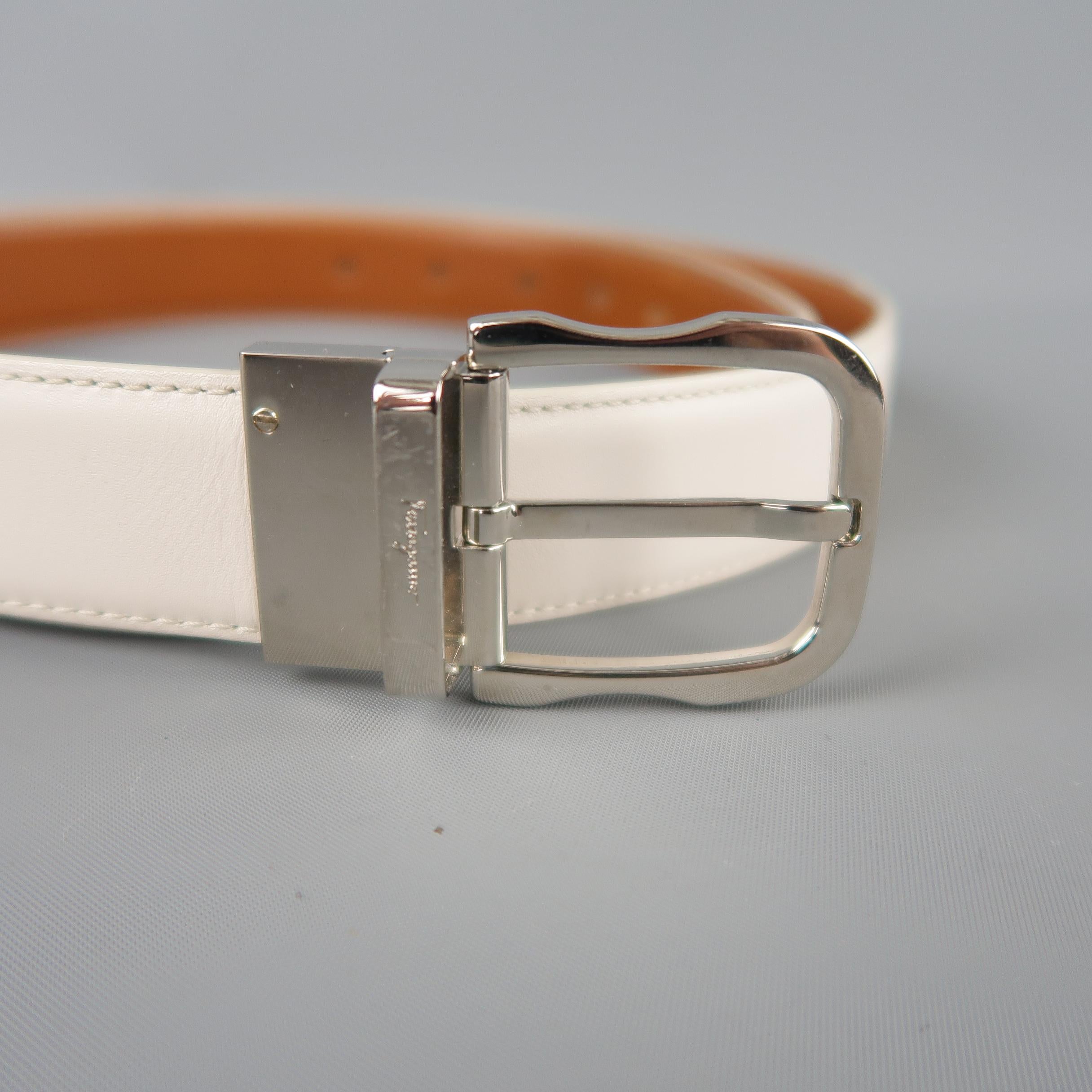 SALVATORE FERRAGAMO reversible dress belt features a dual tone white and tan smooth leather strap with silver tone engraved buckle. Made in Italy.
 
Good Pre-Owned Condition.
Marked: (no size)
 
Length: 46 in.
Width: 1 in.
Fits: 38-42 in.