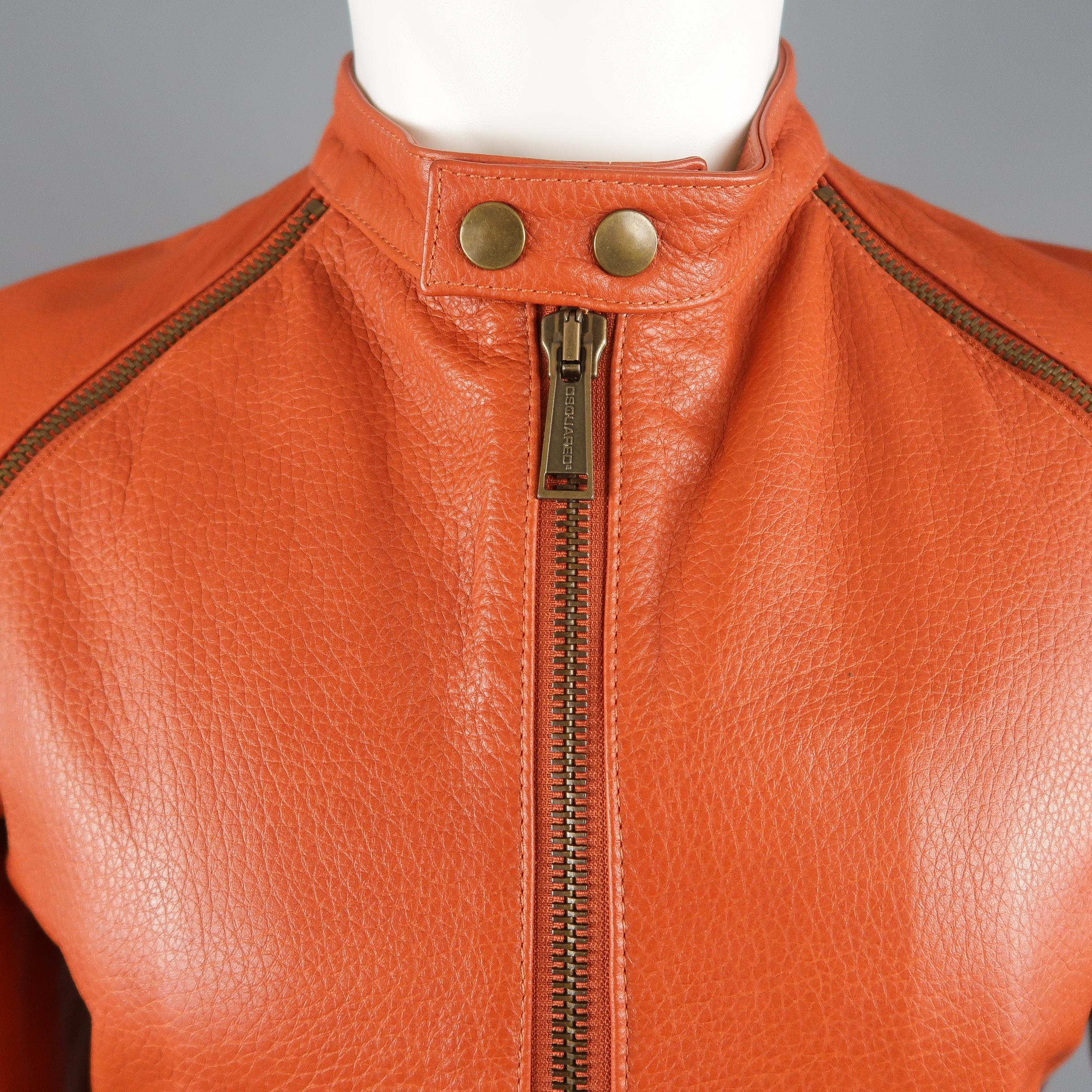 DSQUARED2 biker jacket comes in orange textured leather with a band snap over collar, double zip up front, gathered side panels, and antique gold tone zip sleeves. Minor wear shown in detail shots. Made in Italy.
 
Good Pre-Owned Condition.
Marked: