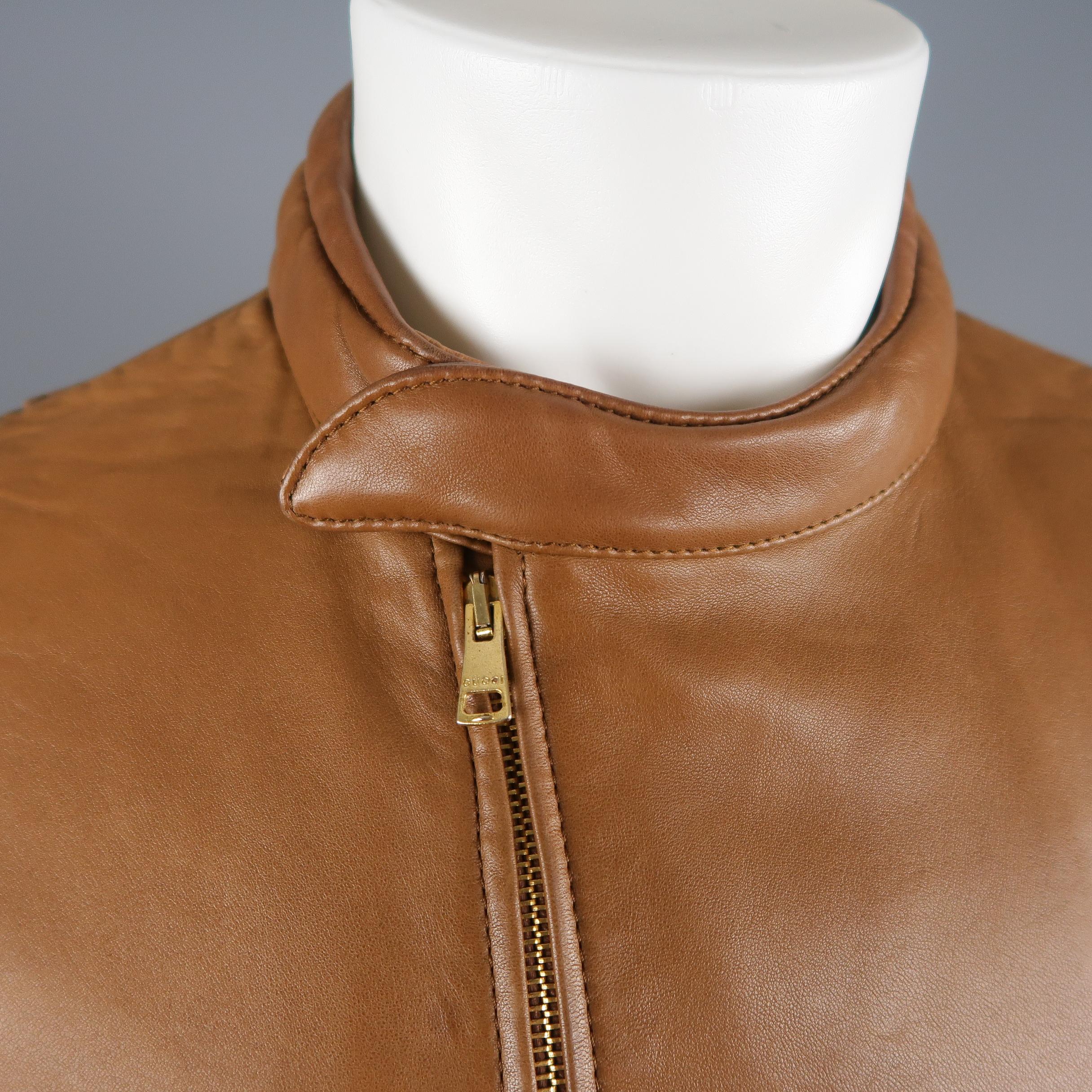 Archive Gucci By Tom Ford biker style jacket comes in soft tan leather and features a band collar with curved hidden snap closure, double zip front, logo embossed waist closure, zip pockets, perforated panels, zip cuffs, and arm pads. Wear