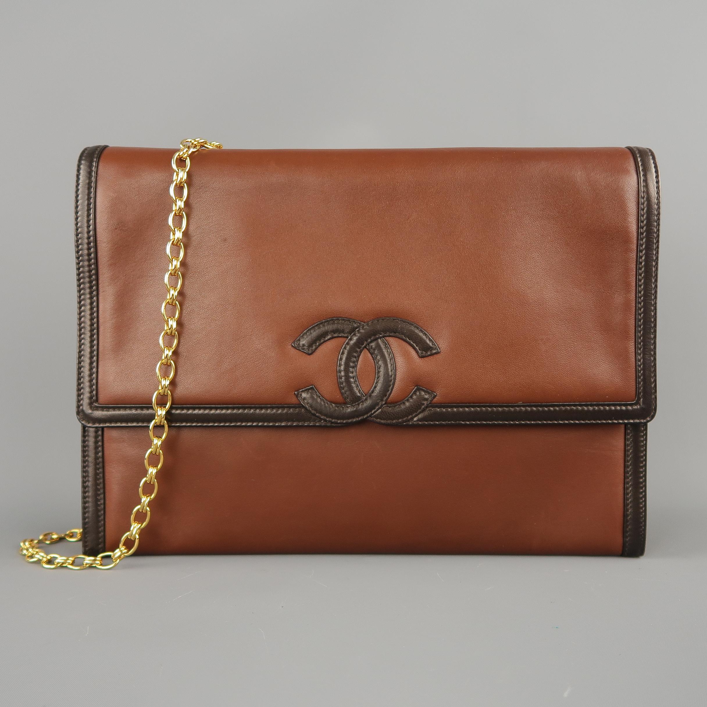 This rare vintage 1980's Chanel handbag comes in smooth brown leather in a classic rectangular shape with a top flap closure, yellow gold tone chain strap, dark brown leather piping and CC logo, and leather interior with pockets. Gifted by The