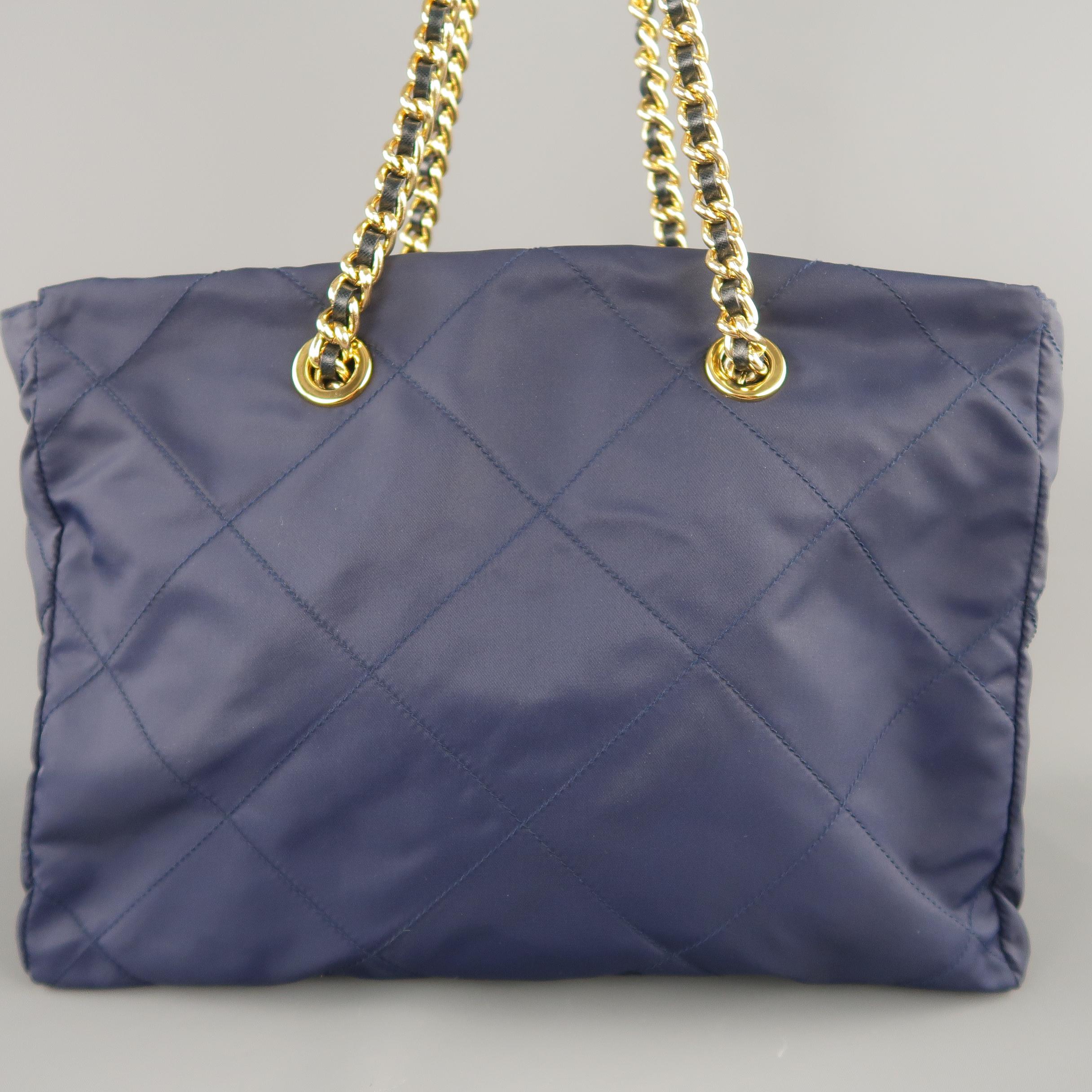 This rare vintage Prada handbag comes in quilted nylon twill with gold tone, grommet accented double leather woven chain shoulder straps, enamel side plaque, and top zip closure. Gifted from The Getty's, purchased at Bergdorf Goodman with box. No