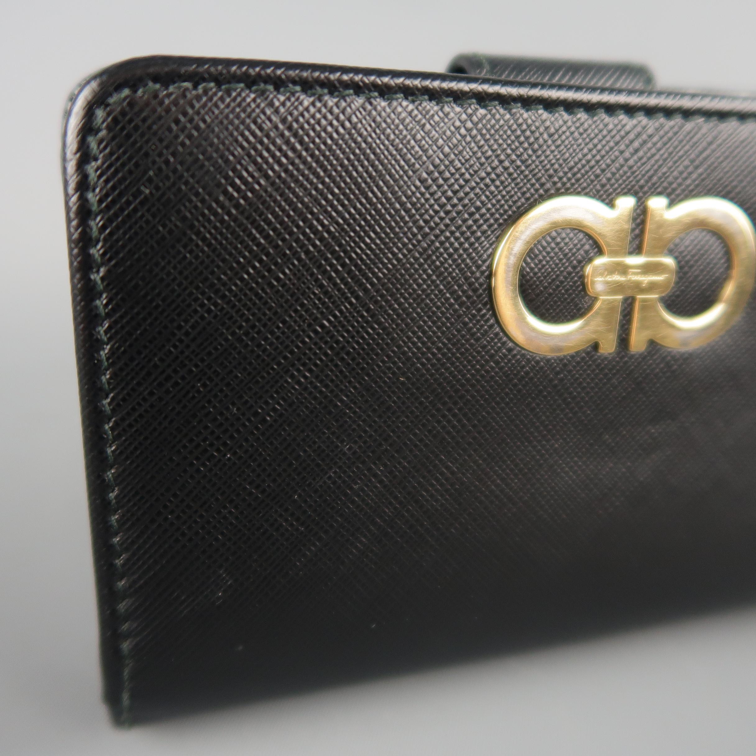 SALVATORE FERRAGAMO wallet comes in black Saffiano textured leather with a snap tab card slot compartment, zip pouch, and gold tone double Gancini logo embellishment. Some Discoloration on hardware. Made in Italy.
 
Good Pre-Owned Condition.
