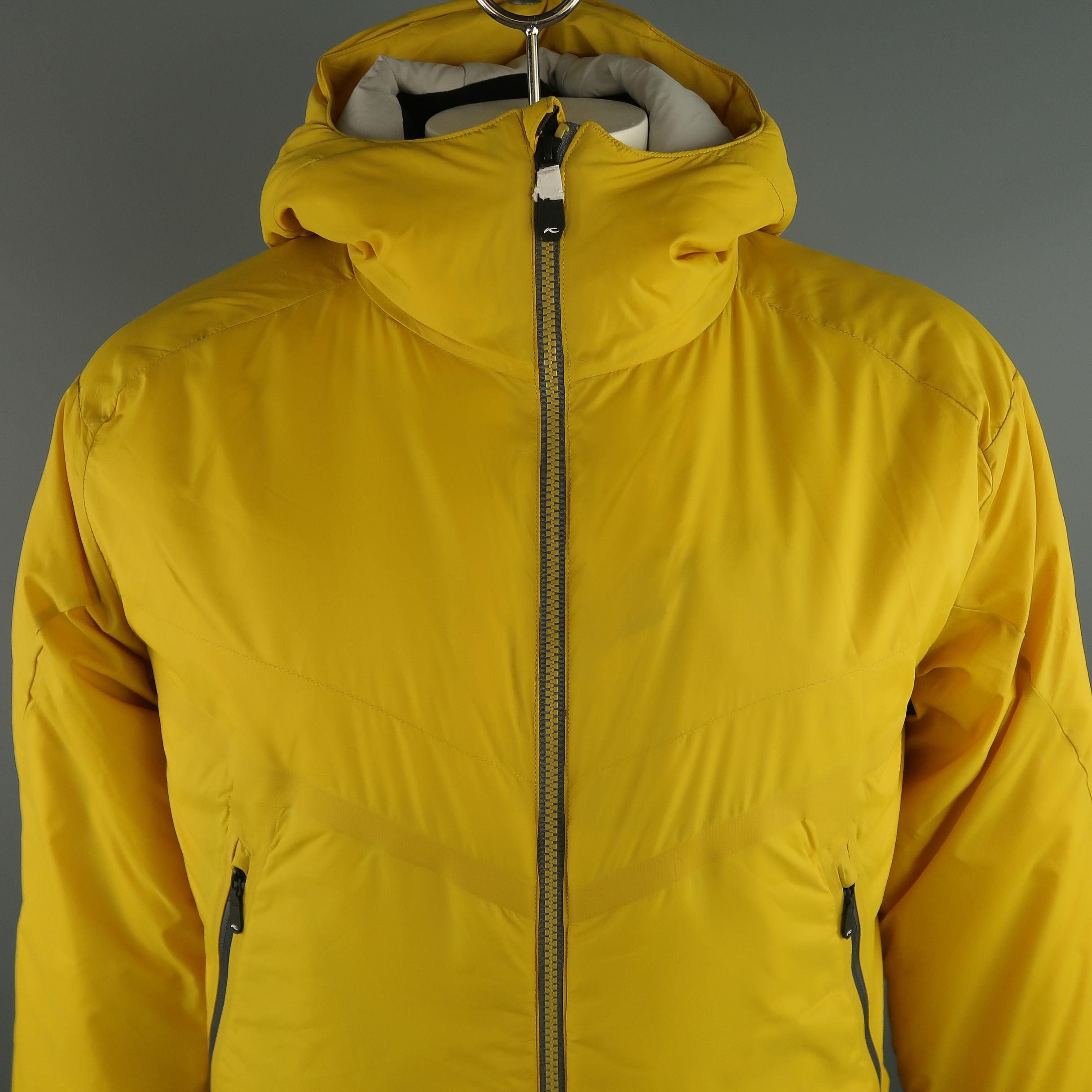 KJUS  filled hooded  jacket comes in a light weight yellow tone in polyamide solid material, zip up, slit pockets. Made in Italy.
 
New without Tags.
Marked: 52 / L  
 
Measurements:
 
Shoulder: 20 in.
Chest: 46 in.
Sleeve: 27 in.
Length: 30 in.