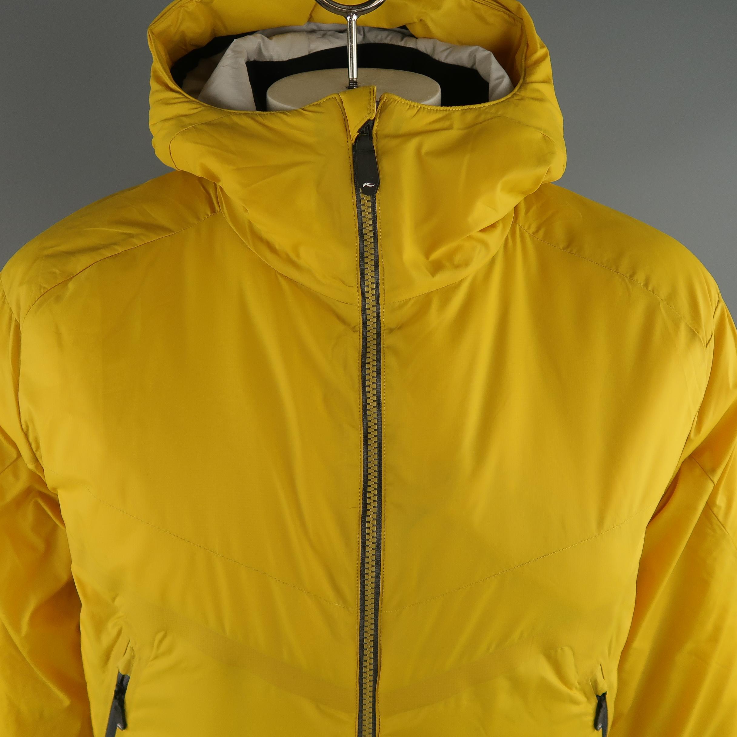 KJUS  filled hooded  jacket comes in a light weight yellow tone in polyamide solid material, zip up, slit pockets. Made in Italy.
 
New with Tags.
Marked: 52 / L  
 
Measurements:
 
Shoulder: 20 in.
Chest: 46 in.
Sleeve: 27 in.
Length: 30 in.