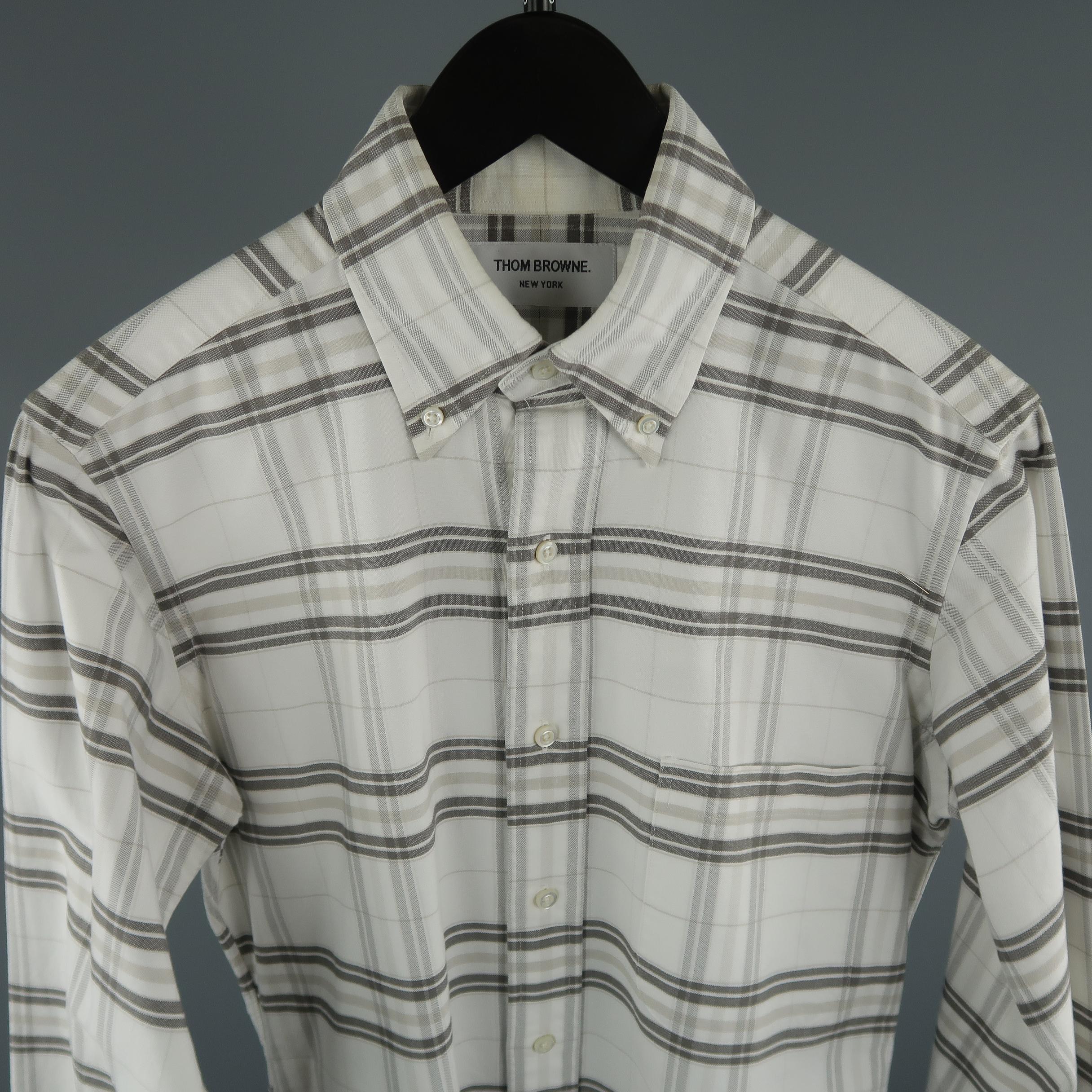 THOM BROWNE for BERGDORF GOODMAN shirt come in tones of white and grey, in a plaid cotton with a front patch pocket, button down collar and long sleeves. Presenting a very light stain inside the collar. Made in USA.
 
Excellent  Pre-Owned