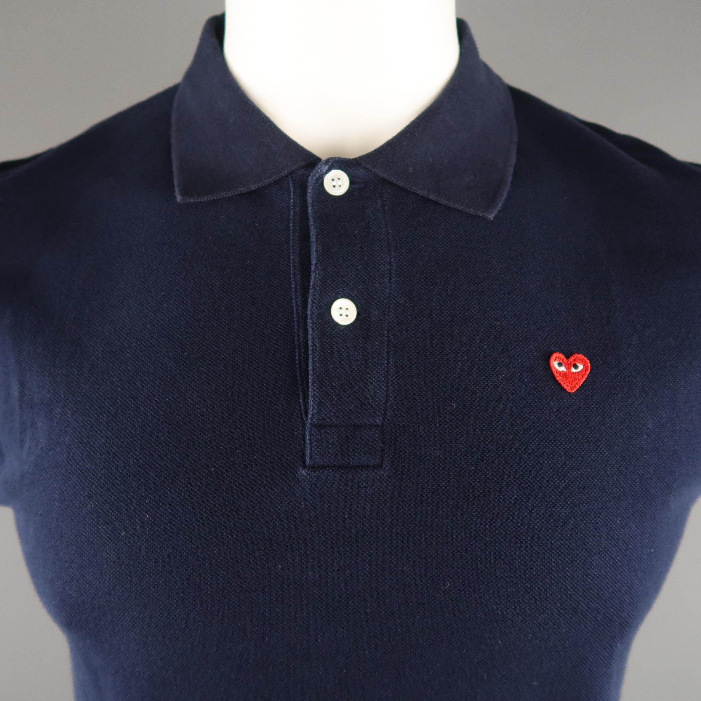 PLAY by COMME DES GARCONS POLO shirt comes in a navy solid pique cotton with contrast red logo and buttoned.  Minor wear.
 
Good Pre-Owned Condition.
Marked: L
 
Measurements:
 
Shoulder: 18.5  in.
Chest: 40 in.
Sleeve: 7.5 in.
Length: 27.5  in.