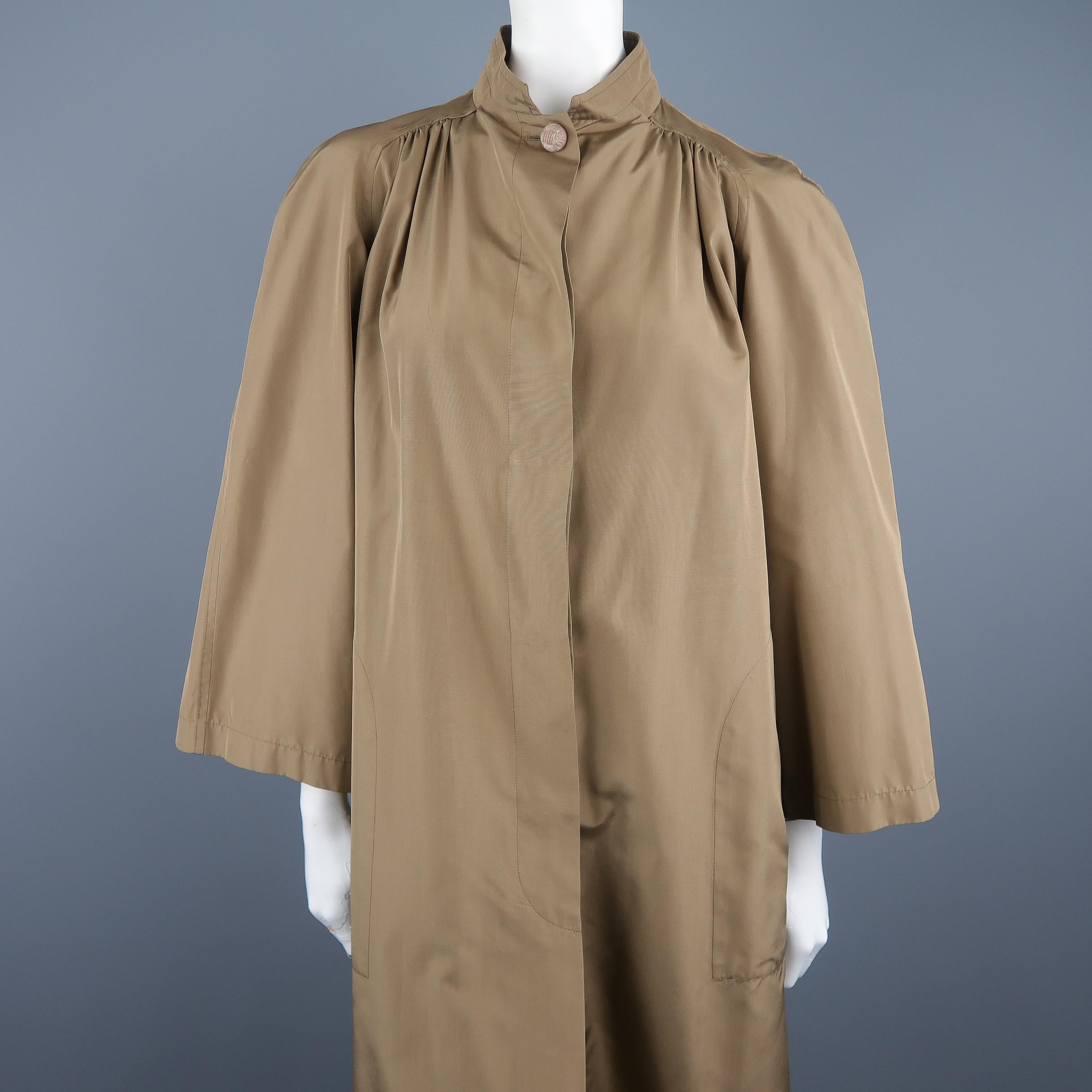 Vintage VALENTINO Boutique overcoat comes in tan taffeta with a stand up collar, wide cropped sleeve, gathered shoulders, hidden placket button up closure, and oversized A line silhouette. Made in France.
 
Excellent Pre-Owned Condition.
Marked: (no