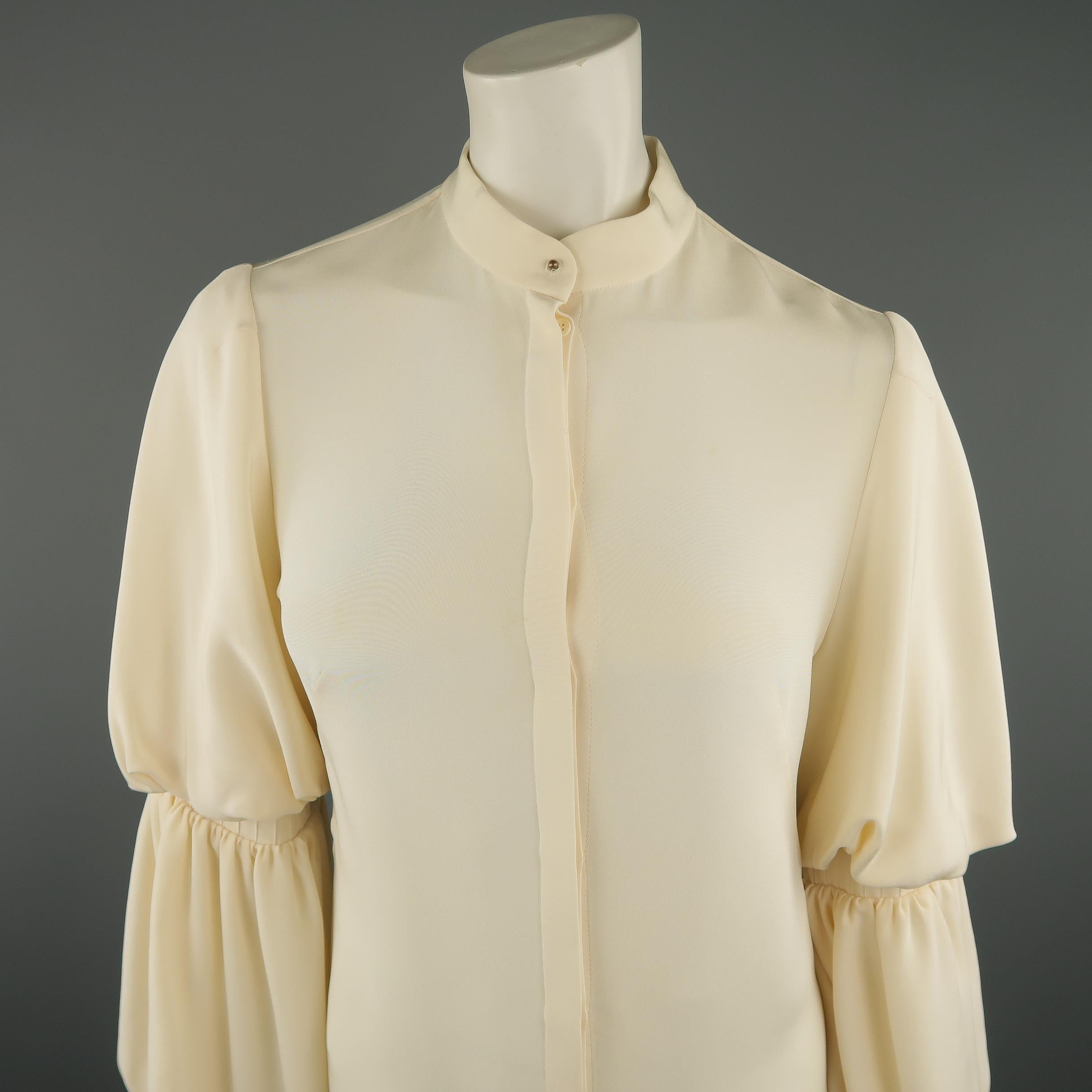 
ALEXANDER MCQUEEN blouse comes in creamy beige silk with a band collar, hidden placket button closure, and layered puff bishop sleeves with pleated ruffle cuffs. Faint discolorations shown in detail shots. Made in Italy.
 
Good Pre-Owned