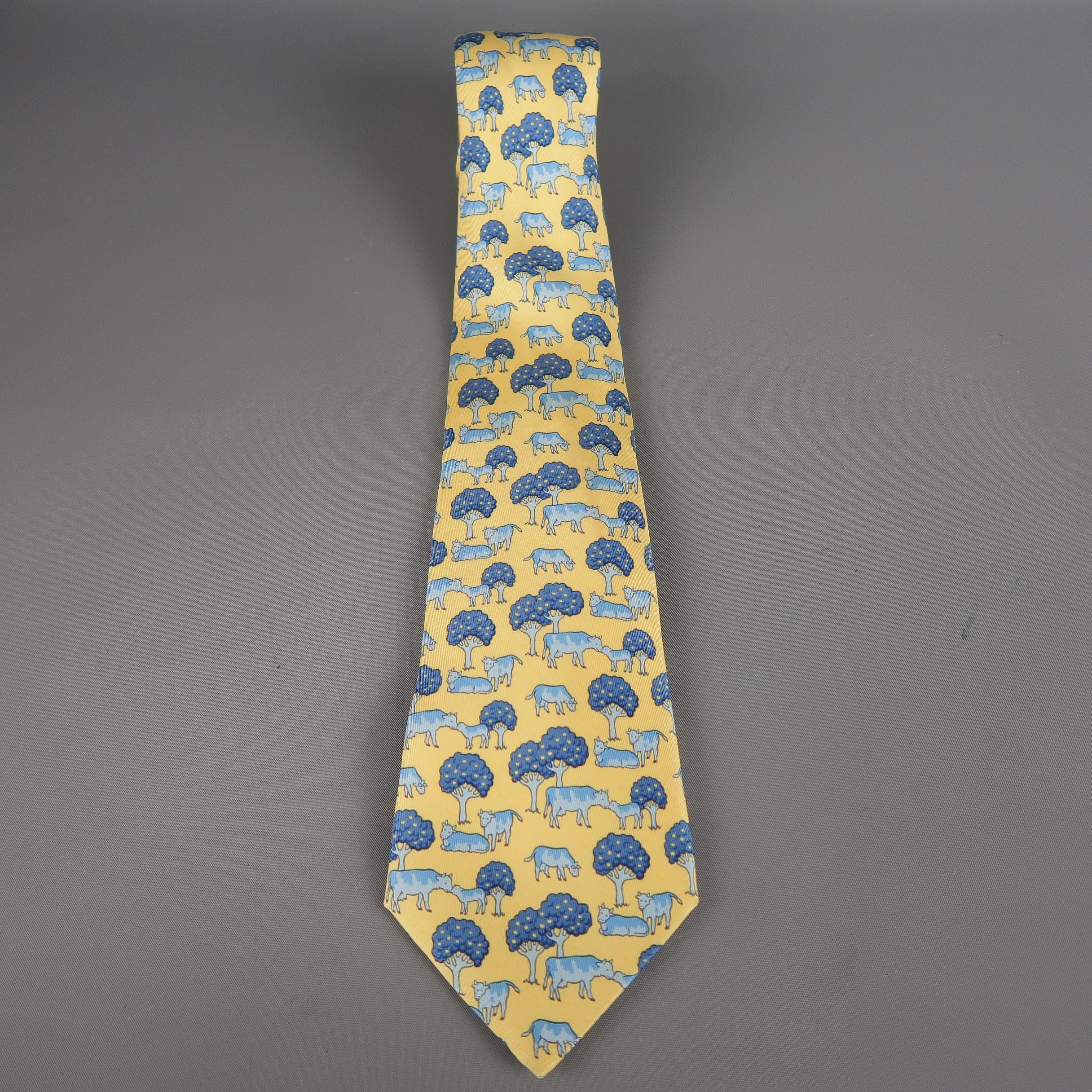 Yellow and blue silk necktie by HERMES.  This piece comes in an all-over cow and tree print.  Made in France.
 
Excellent Pre-Owned Condition.
 
Marked As: 7527 IA