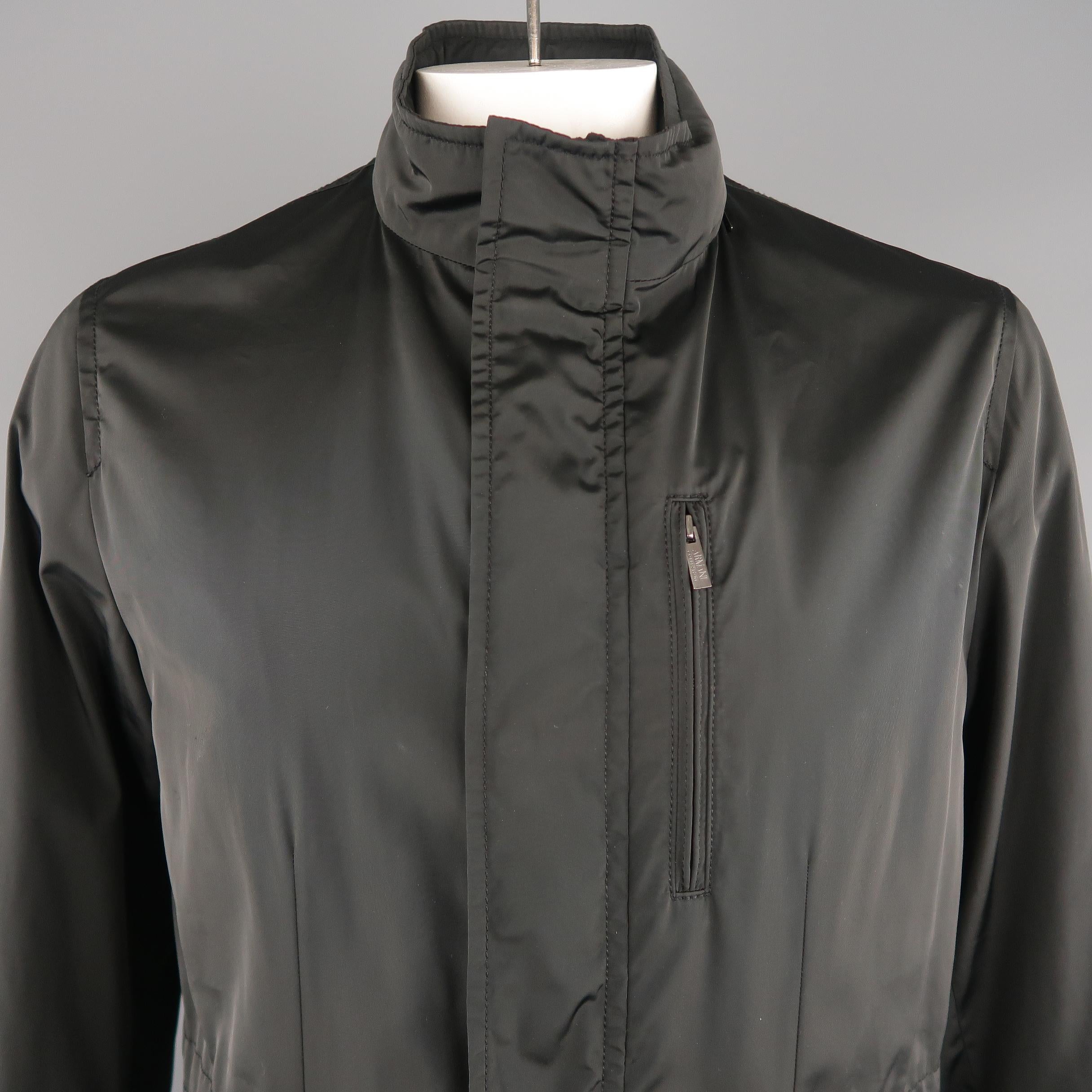 ARMANI COLLEZIONI water repellent  jacket comes in black tone in solid polyester material, with a hoodie,  front zip and flap pockets, zips and snaps.  
 
Excellent  Pre-Owned Condition.
Marked: 40
 
Measurements:
 
Shoulder:  17.5  in.
Chest: 44 