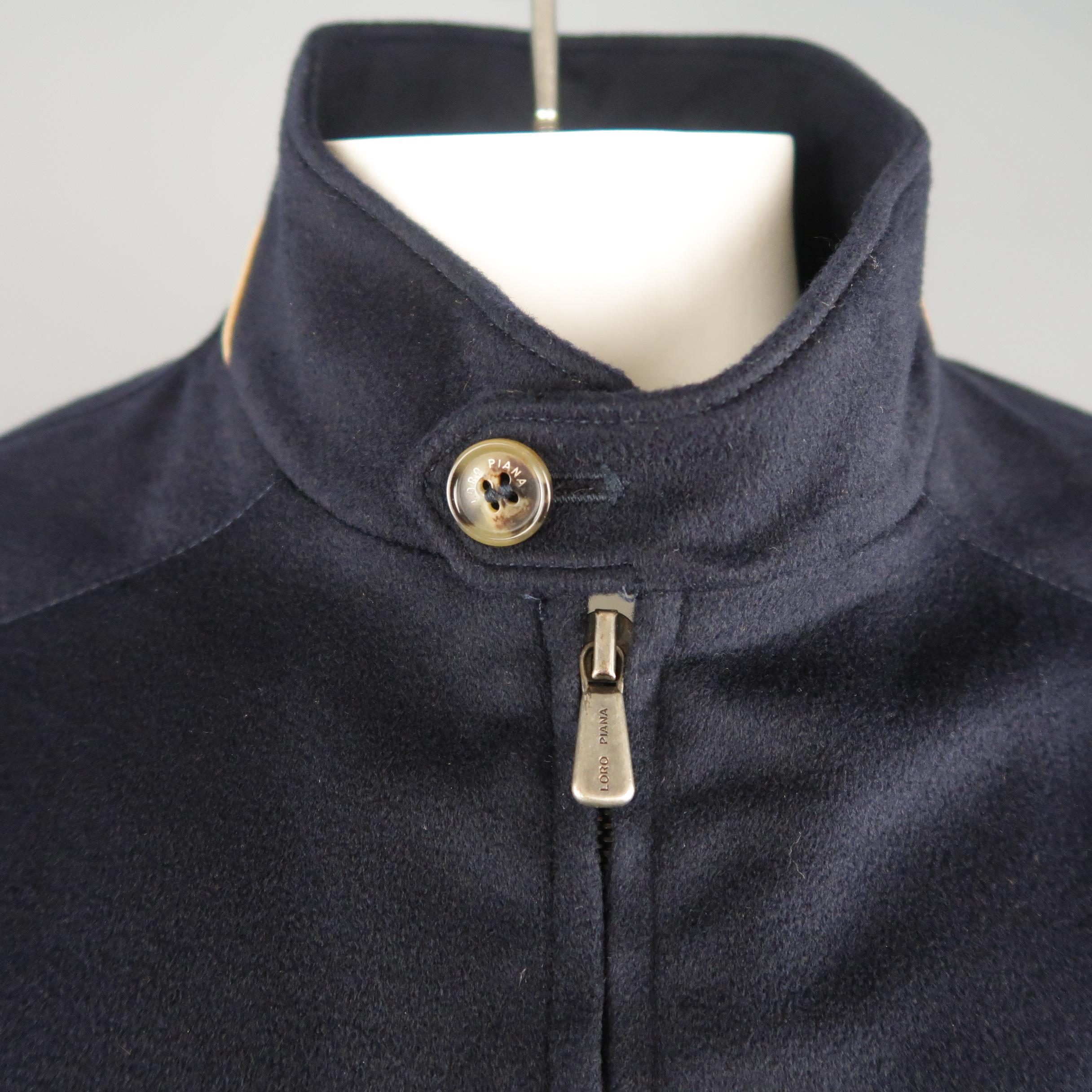 LORO PIANA Storm System jacket comes in navy cashmere with a high button collar, double zip front, slanted zip pockets, and tan suede trim. Made In Italy. Retail price $ 2,695.00
 
New without Tags.
Marked: XL
 
Measurements:
 
Shoulder: 20