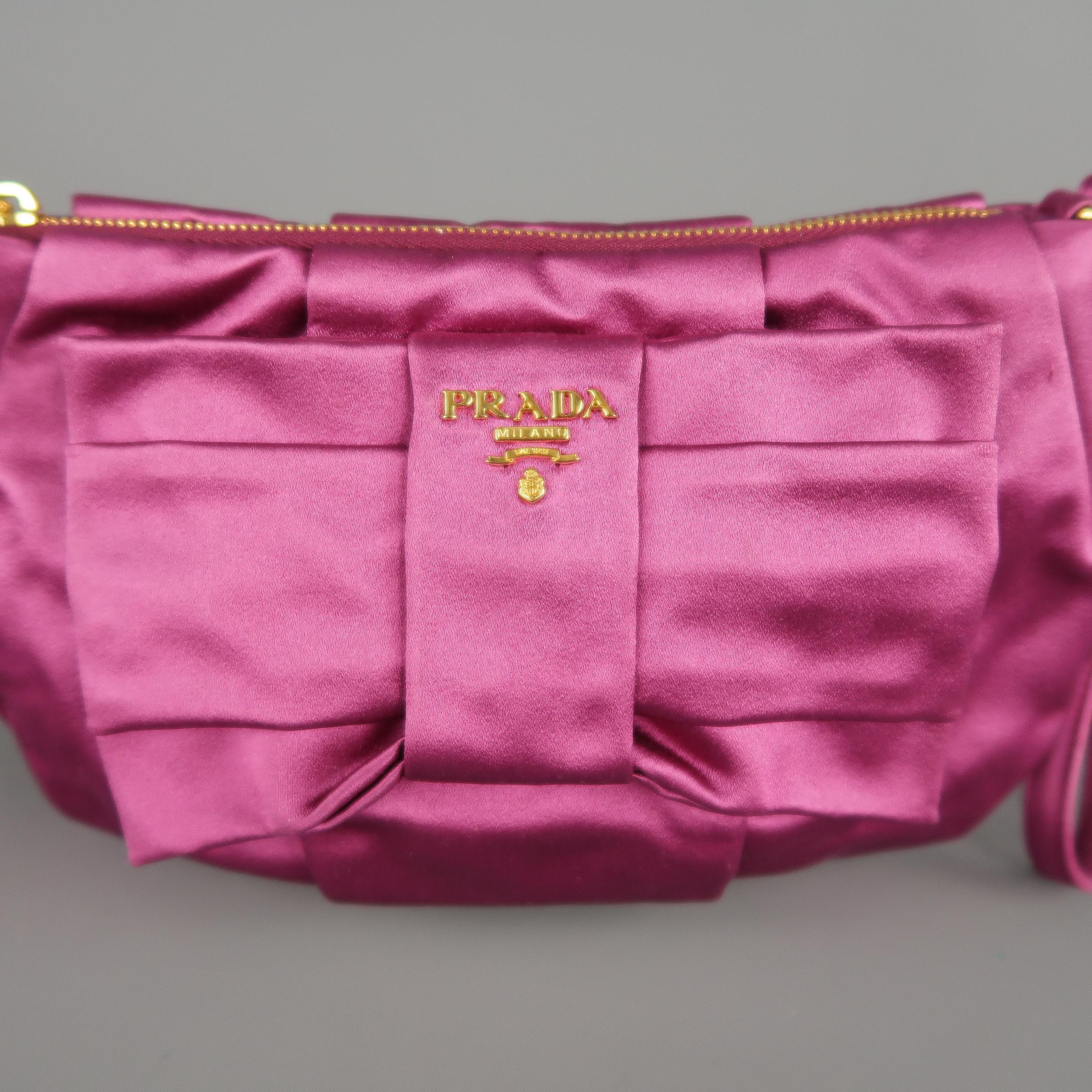PRADA wristlet pouch bag comes in jewel tone pink silk satin with an oversized bow, gold tone metal logo, top zip, and detachable strap. Made in Italy.  Retail: $425.00
 
Excellent Pre-Owned Condition.
 
Measurements:
 
Length: 10 in.
Width: 1