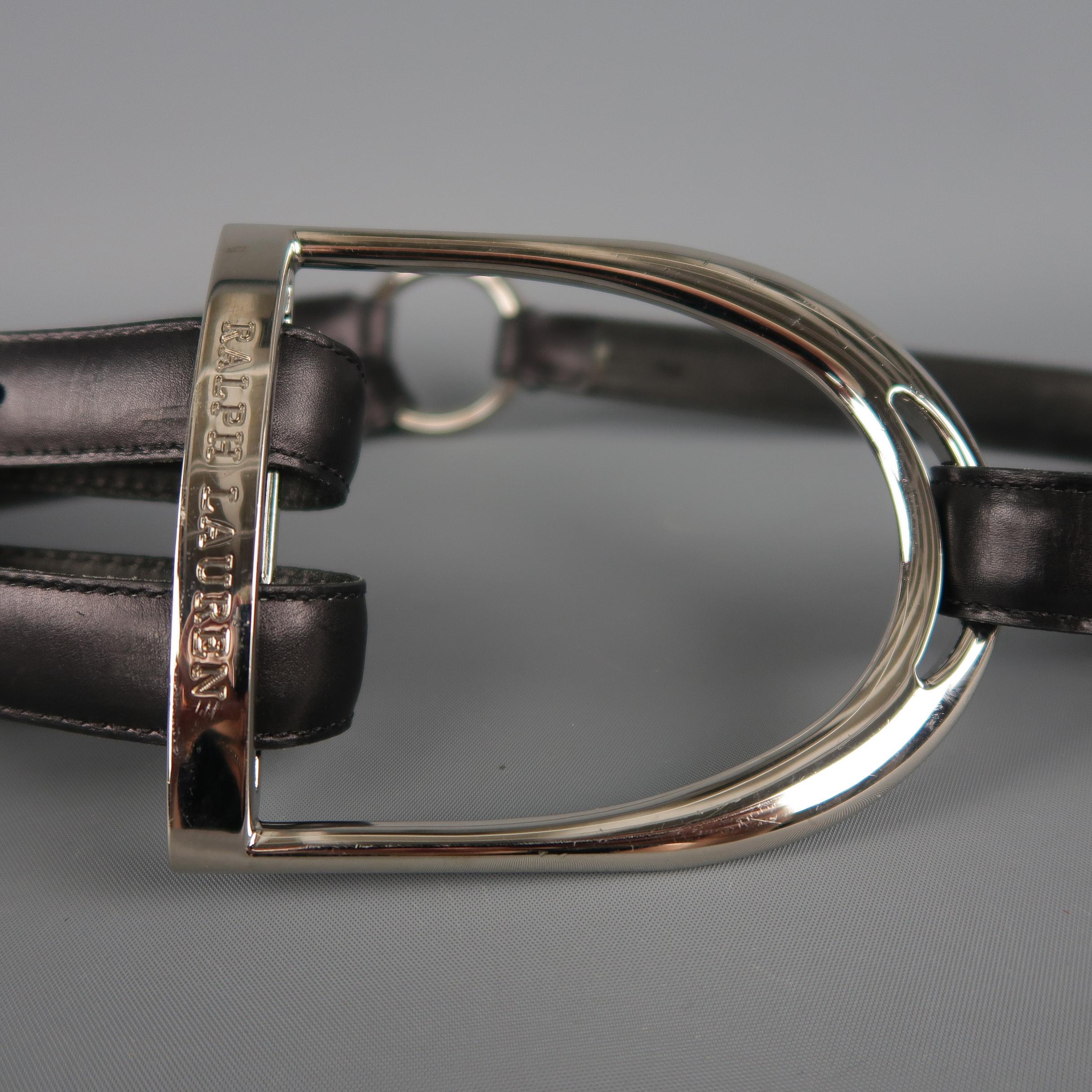 RALPH LAUREN statement belt features an oversized embossed silver tone Equestrian D ring with a double black leather strap, silver tone hoop, and single strap side. Made in England.  Retail: $695.00
 
Very Good Pre-Owned Condition.
Marked: S

