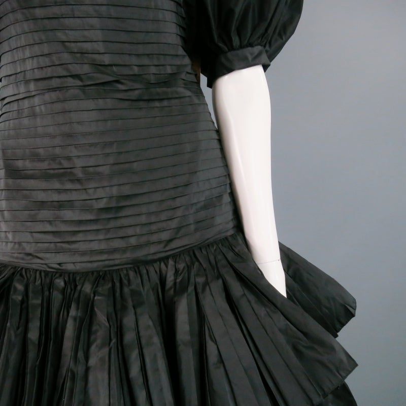 Stunning 1980's vintage cocktail dress by OSCAR DE LE RENTA. In a beautiful black silk taffeta, featuring puff sleeve, pleated drop-waist bodice, and ruffled skirt. Made in USA.

Excellent Pre-Owned Condition.
 
Measurements:
 
Bust: 36