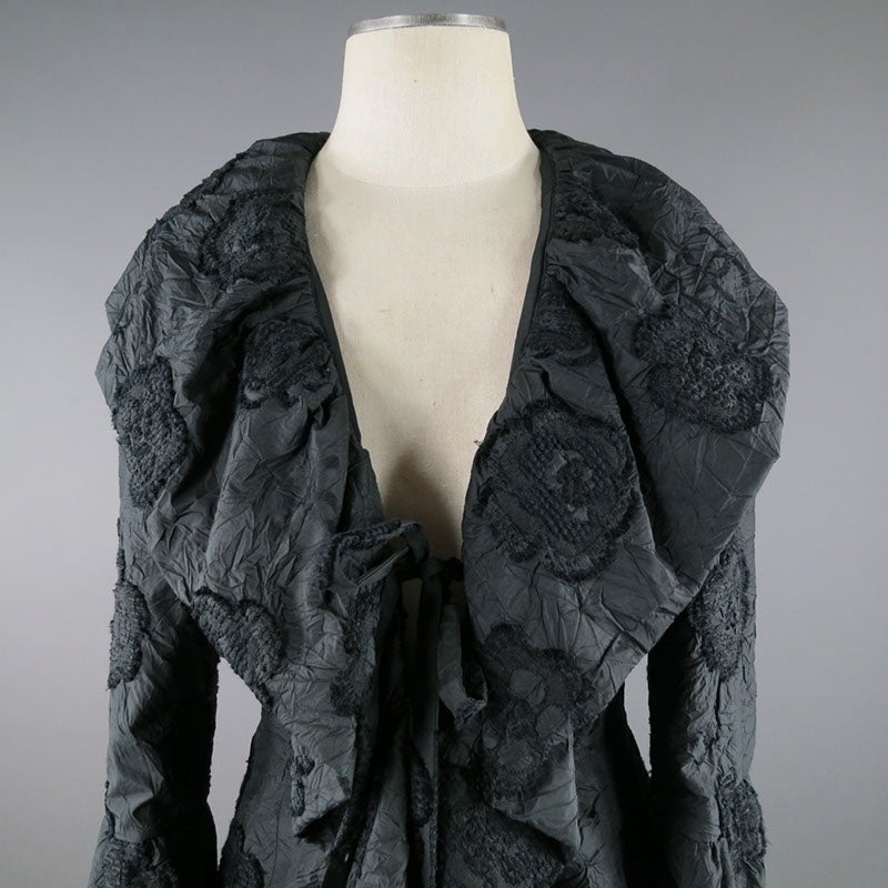 This divine black Chanel jacket features a floral design motif complimented by a crumpled texture. In addition this one of a kind jacket features a shawl collar with a silk front tie. This garment is absolute perfection.
Made in France.
