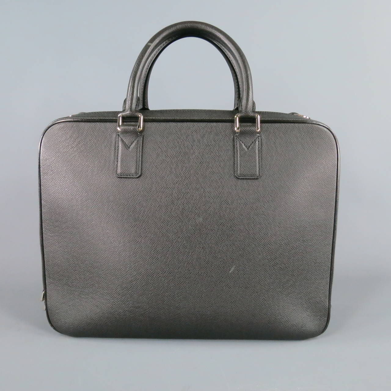 Classic double compartment briefcase by LOUIS VUITTON. This rectangular top handles style comes in black taiga textured leather, featuring one external pocket with handle, zip compartment with organizer sections complete with key hoop, and second