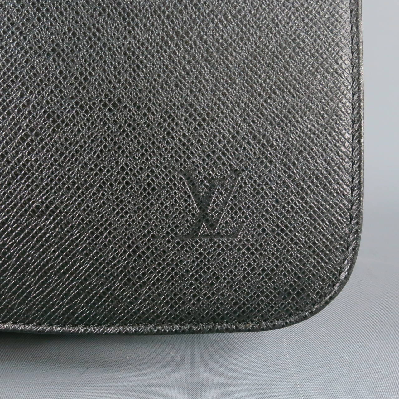 Classic messenger bag by LOUIS VUITTON. The VIKTOR comes in a black taiga textured leather with cloth back and features a flap closure embossed with 