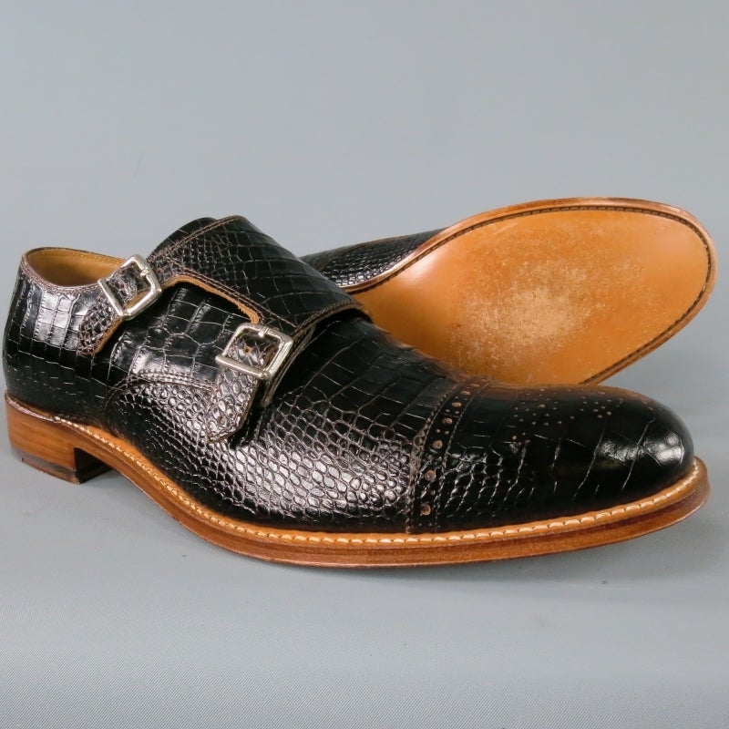 Grenson Monk-Strap Shoes consists of a black embossed leather material with contrast wood sole. Designed with a monk strap closure that features two silver buckles, cap-toe with perforated detail and wing-tip front. Embossed 