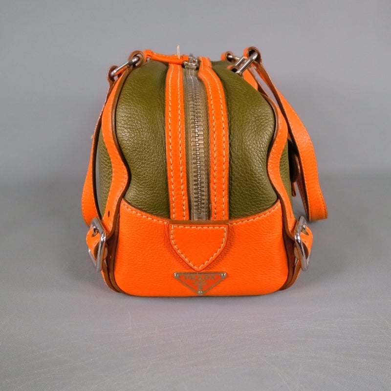Olive and orange leather bowler bag by PRADA. Featuring silver belt buckle details, slanted front zipper, double zip closure, and detachable luggage tag. Made in Italy.
 
Excellent Pre-Owned Condition.
 
Measurements:
 
Length: 14 in.
Width:
