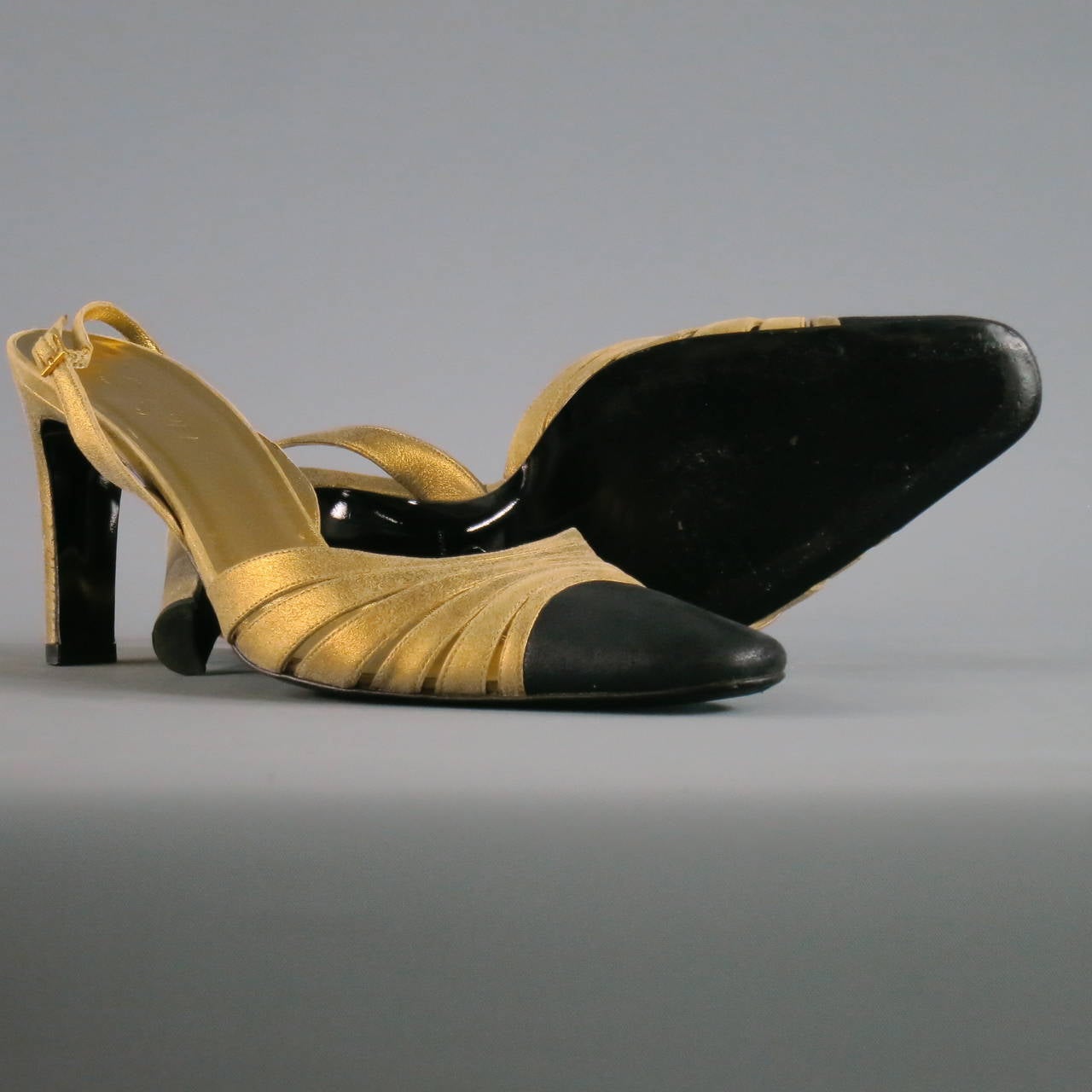 Classic gold and black suede sling-back pumps from Chanel. The condition of this pair is AS-IS: missing gold stitched logo on right shoe and small blemish on back of heel. Note: Pumps appear more of a polished gold in photos, yet they are