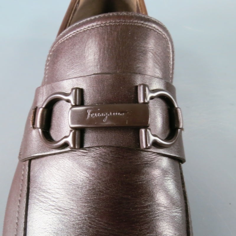 Salvatore Ferragamo Slip On Loafers consists of a leather material in a cherry brown color tone. Designed with a athletic, luxe look, brown gancini bit across tongue with engraved logo. Stitched mock toe with sporty rubber sole that contours into