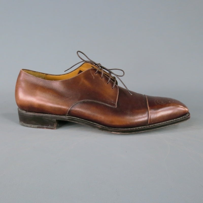 Salvatore Ferragamo Lace Up Shoe consists of a leather material in a brown color tone. Designed with a cap-toe stitch, perforated wingtip front and tone-on-tone stitching throughout vamp. Square toe front with contrast brown sole. Made in Italy.
