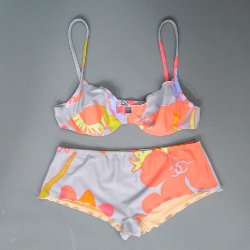 Fabulous two piece bathing suit by CHANEL. A fun resort style in vibrant peach, lavender, green, and fuschia floral print over silver stretch lycra featuring an under wire, thin strap bra top with 