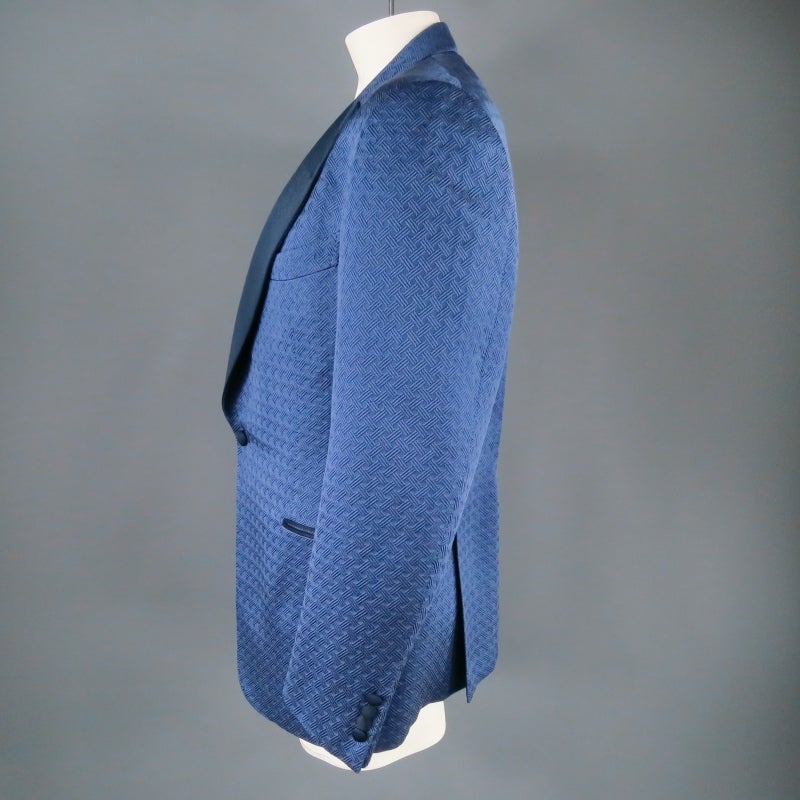 Stunning single button Dinner Jacket by TOM FORD. This piece features a beautiful navy woven pattern in a silk/cotton blend, wide contrast peak lapel in black, slit pockets, and double side vents. Made in Italy.
 
Excellent Pre-Owned Condition.
