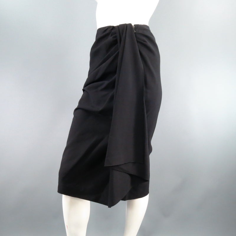 Gorgeous black wool pencil skirt by LANVIN. A a unique style in light weight black wool, this piece features a draped front that ruches from one side and gathers to a flowing column. Circa 2007. Made in France.
 
Excellent Pre-Owned Condition.	Tag