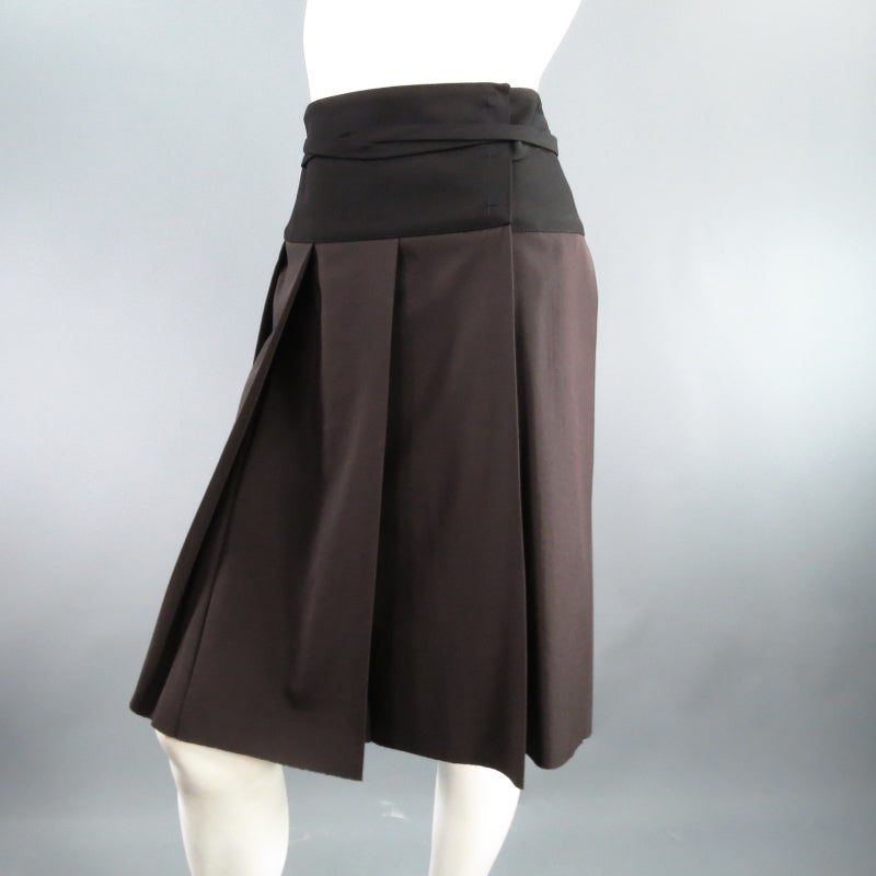 Fabulous two tone wrap skirt by LANVIN. A classic box pleat style in taupe structured wool featuring a black waist panel and ribbon that wraps around the waist and ties in the back. Circa 2006. Made in France.
 
Excellent Pre-Owned Condition.	Tag