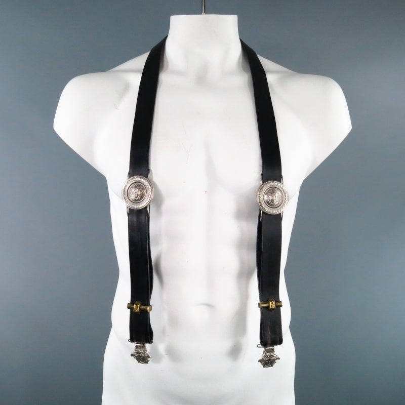 Fabulous vintage GIANNI VERSACE suspenders. A very rare piece from the archives, this piece features adjustable black leather straps with large silver tone Medusa buckles, gold brass  tone Versace nut and bolt hardware, gold tone Medusa hardware on