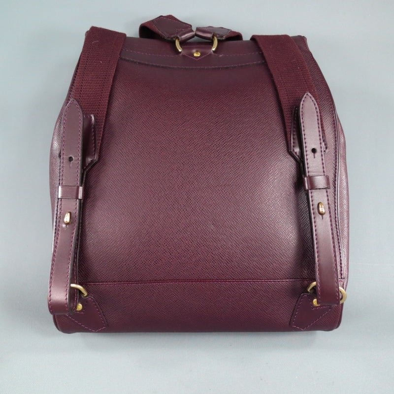 Fabulous luxury backpack by LOUIS VUITTON. The CASSIAR style in color ACAJOU comes in a gorgeous wine colored textured taiga leather and features a flap with gold tone LV embossed hook and eye closure, frontal zip pocket with embossed logo, side