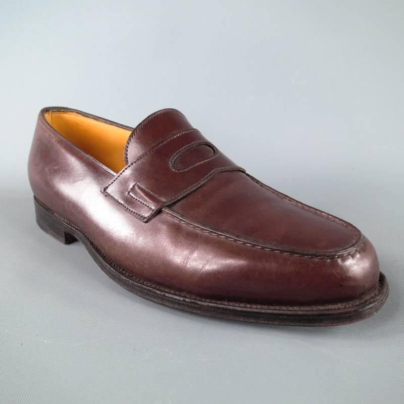 John Lobb "Lopez" Loafer consists of 100% leather material in a brown color tone. Designed with a penny keeper on vamp, hand stitched tone-on-tone detailing can be seen throughout shoe with top edging around the front. Featuring a back