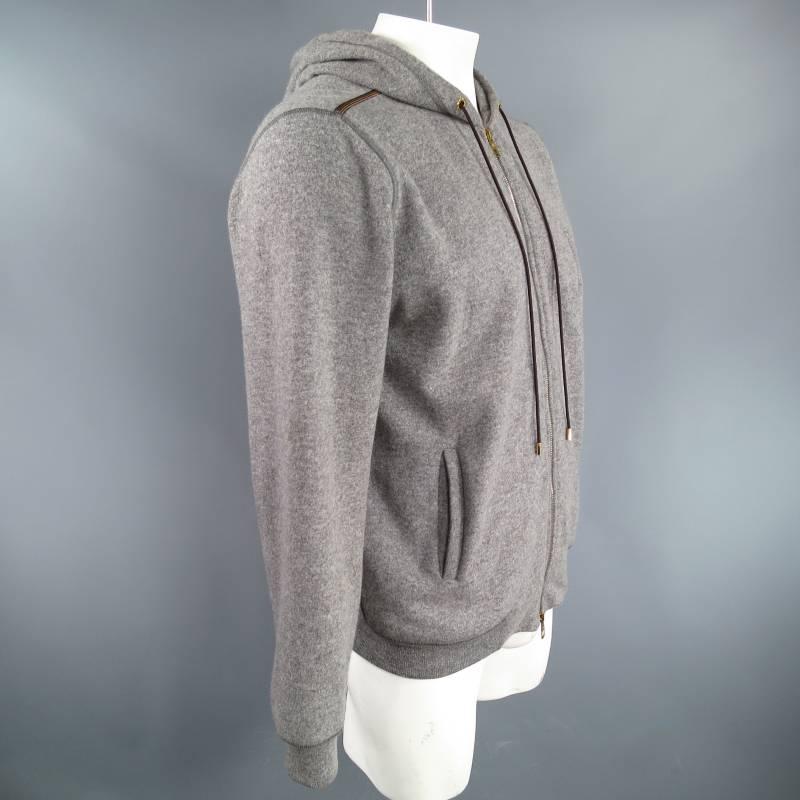 Sumptuous zip up hoodie by LOUIS VUITTON. This piece comes in a wool/ camel hair blend and features gold hardware, dark brown drawstrings, an embroidered embellished monogram, slit pockets, stripe ribbon detail on shoulder, and tone-on-tone