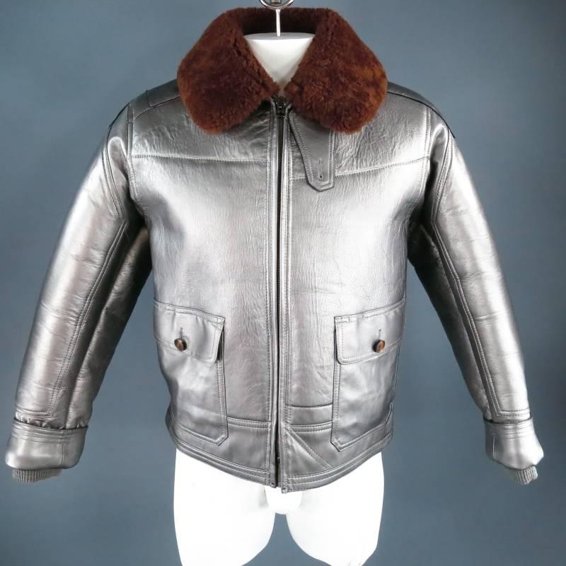 Fabulous RLX by RALPH LAUREN winter jacket. This rare and unique piece comes in a structured metallic silver lambskin and features a brown shearling collar and lining, zip closure, frontal patch pockets, cuffed sleeve with band cuff, side tabs, and