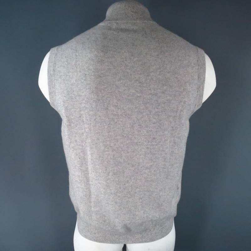 Brunello Cucinelli Sweater Vest consists of 100% cashmere material in a light gray color tone. Designed with rib detailing along high collar and sleeves, shiny charcoal buttons and blousen hem. Made in Italy.
 
Good Pre-Owned Condition
Marked