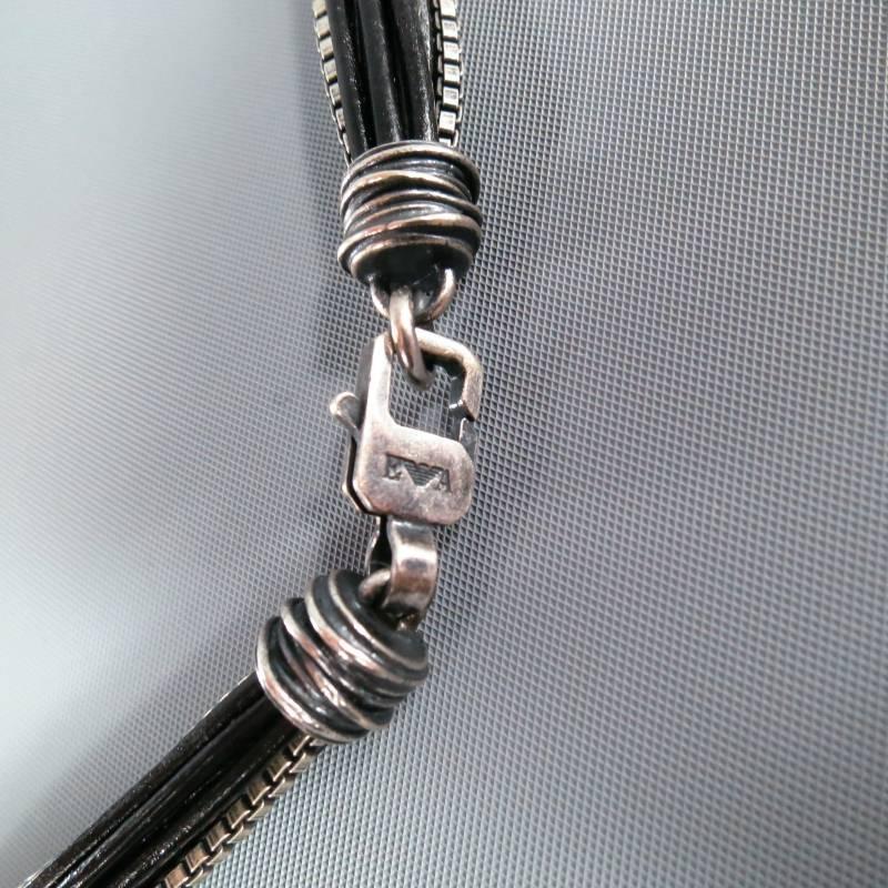 Emporio Armani Necklace consists of 'Sterling Silver' and leather material in a silver and black color tone. Designed with section cut-off that link together, leather piped strings and silver chains are seen throughout length. Engraved edges are
