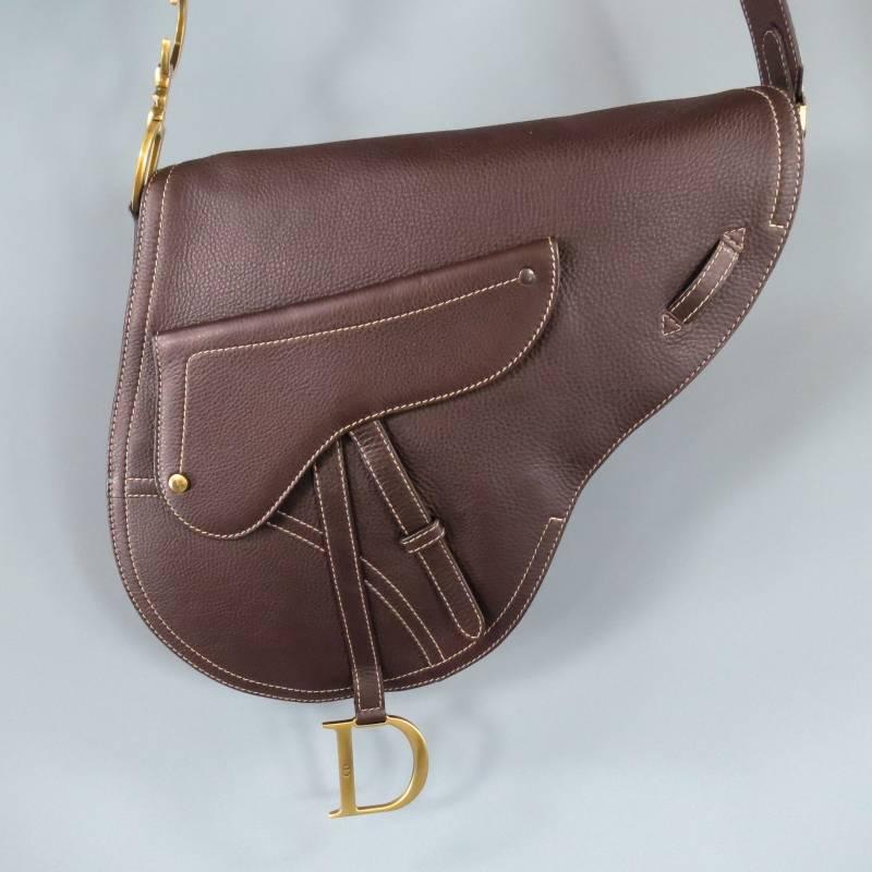 Christian Dior Messenger Bag consists of leather material in brown color tone. Designed in saddle outline shape, contrast white stitching that can be seen throughout body with a front snap/zipper pocket. Flap opening features a heavy brass 