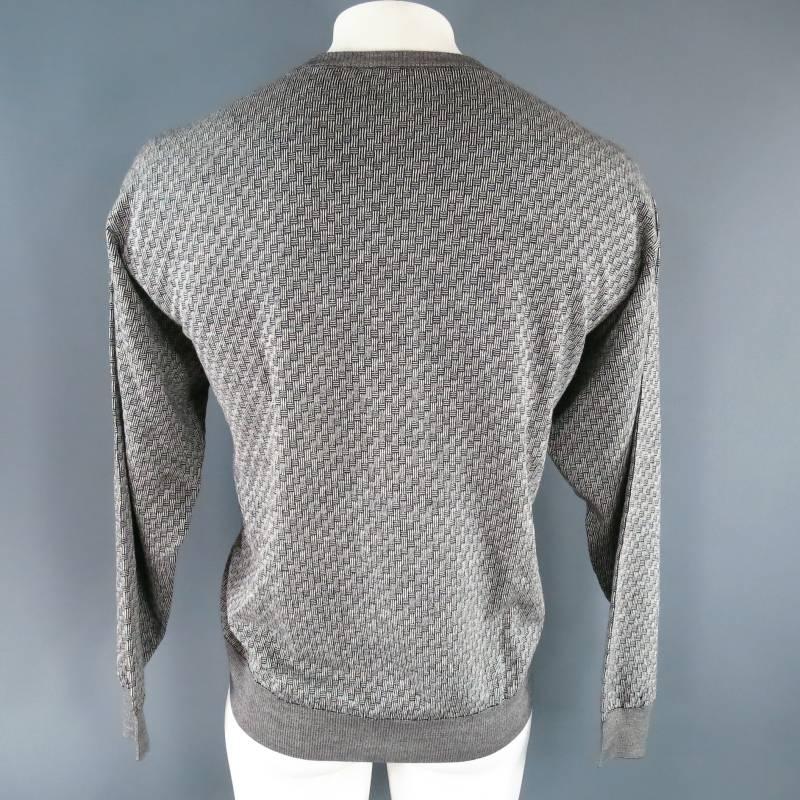 Vintage knit pullover sweater by BRIONI. This classic style with modern appeal comes in a medium weight black and off white wool knit in a unique woven print pattern and features a V neck, long sleeves, and waist and wrist bands.Made in Italy.
