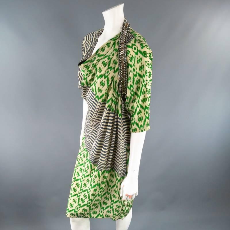 This fabulous cocktail dress by DRIES VAN NOTEN comes in a light weight cream, green, and navy Ikat print silk and features a three quarter sleeve, a line shift silhouette, and an asymmetrical draped neckline with black band embellished with faux